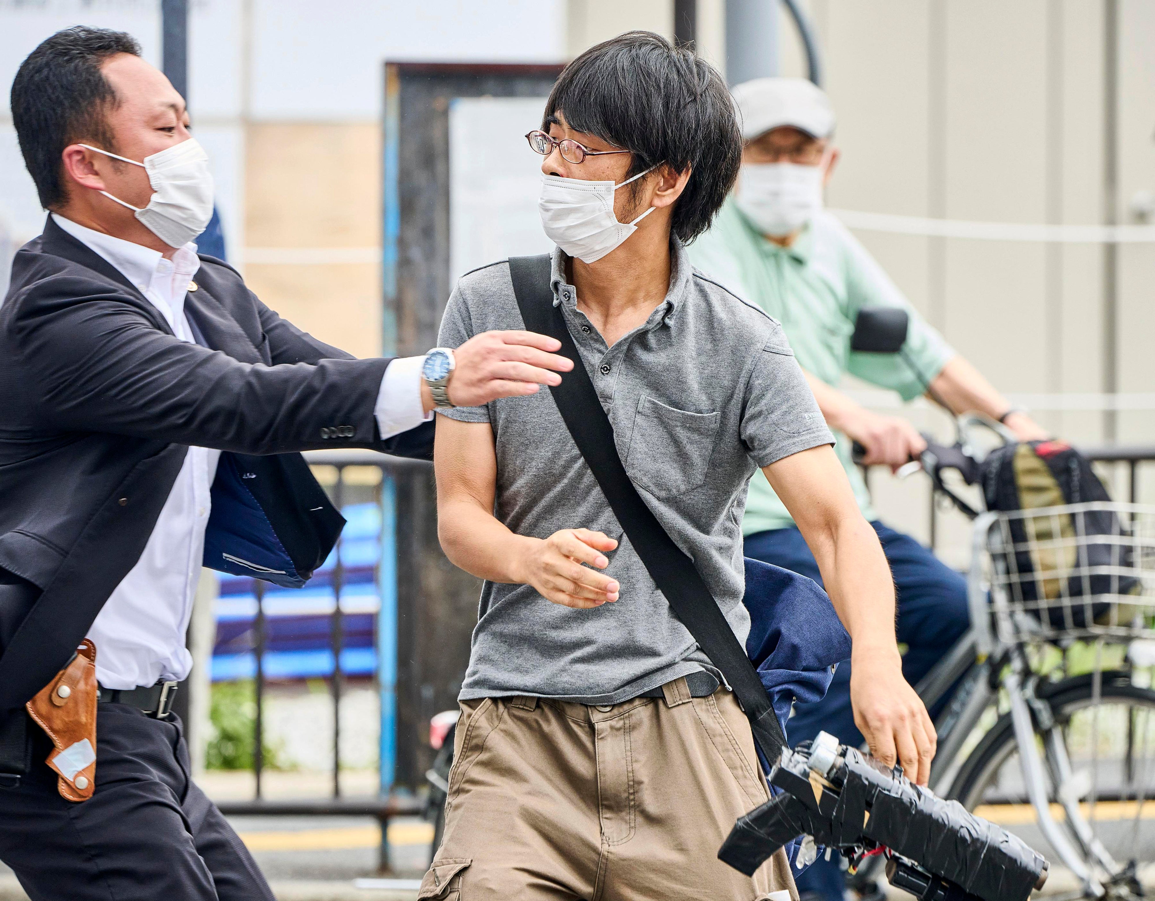 Tetsuya Yamagami (der), sospechoso de asesinar a Shinzo Abe sostiene lo que parece un arma “casera” mientras es detenido en la escena del crimen