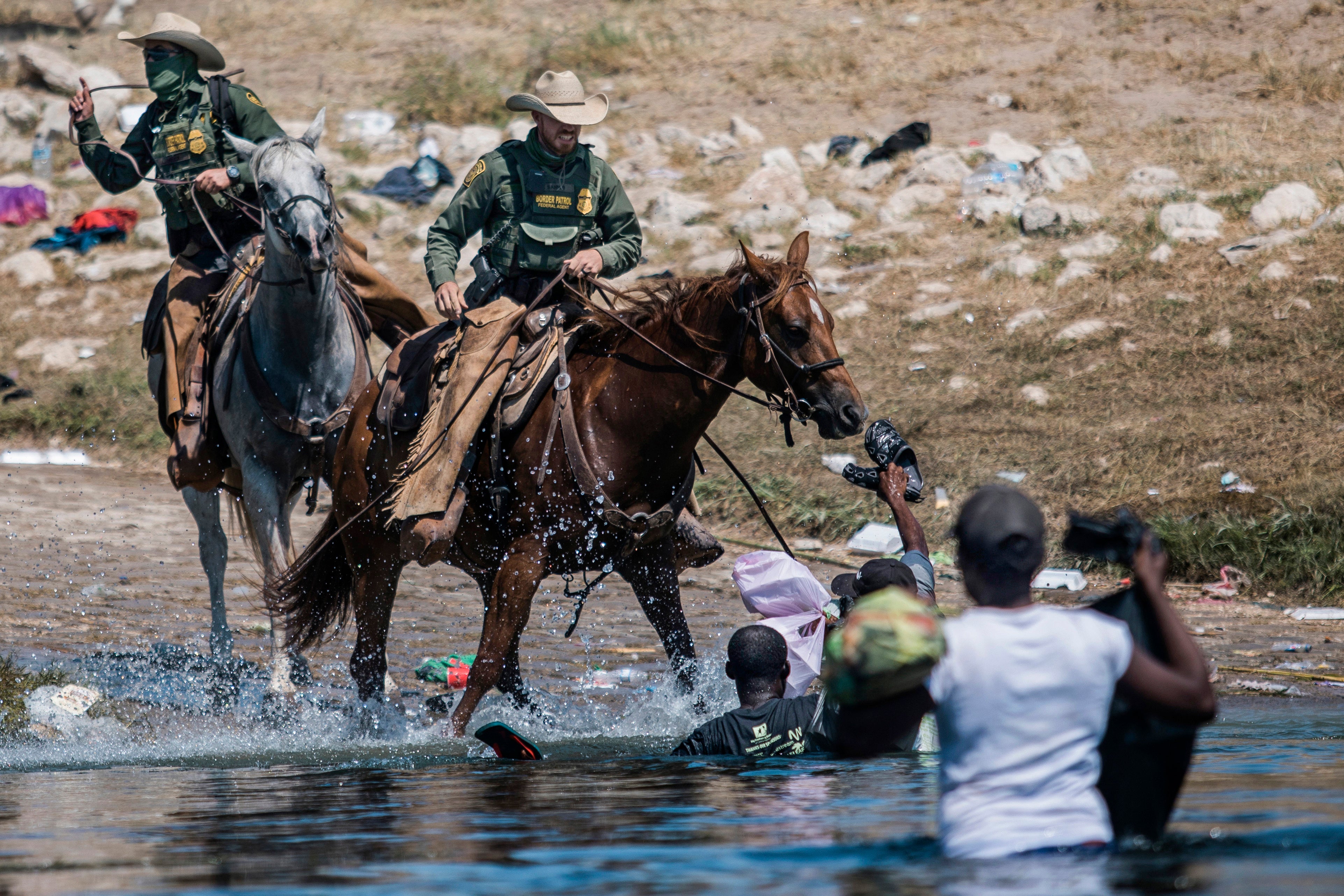 Agentes de la Patrulla Fronteriza de Estados Unidos montados intentan contener a los migrantes mientras cruzan el Río Grande desde Ciudad Acuña, México, hacia Del Río, Texas, 19 de septiembre de 2021