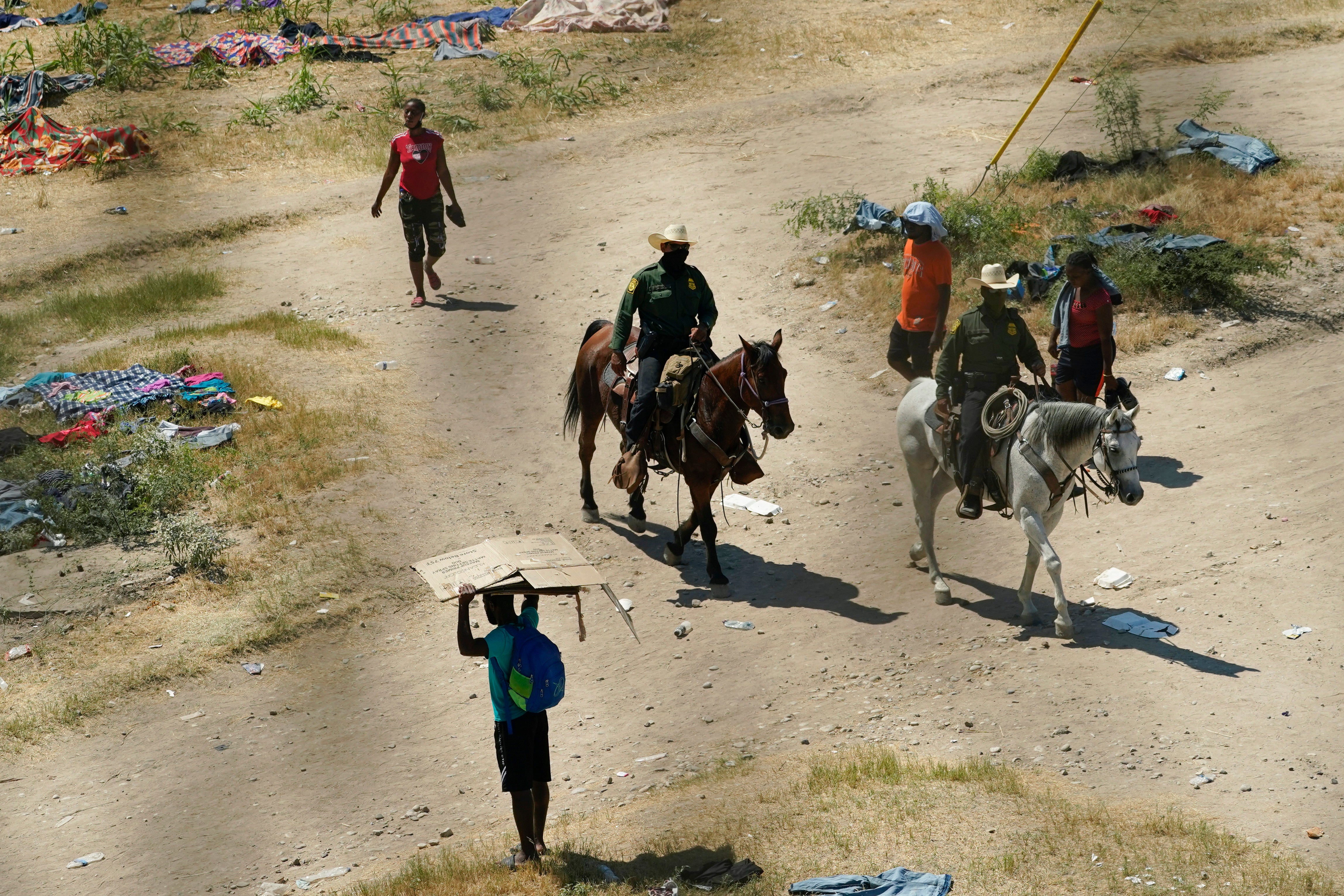 Agentes de la Patrulla Fronteriza se cruzan con migrantes haitianos en un campamento improvisado, el 17 de septiembre de 2021, en Del Río, Texas