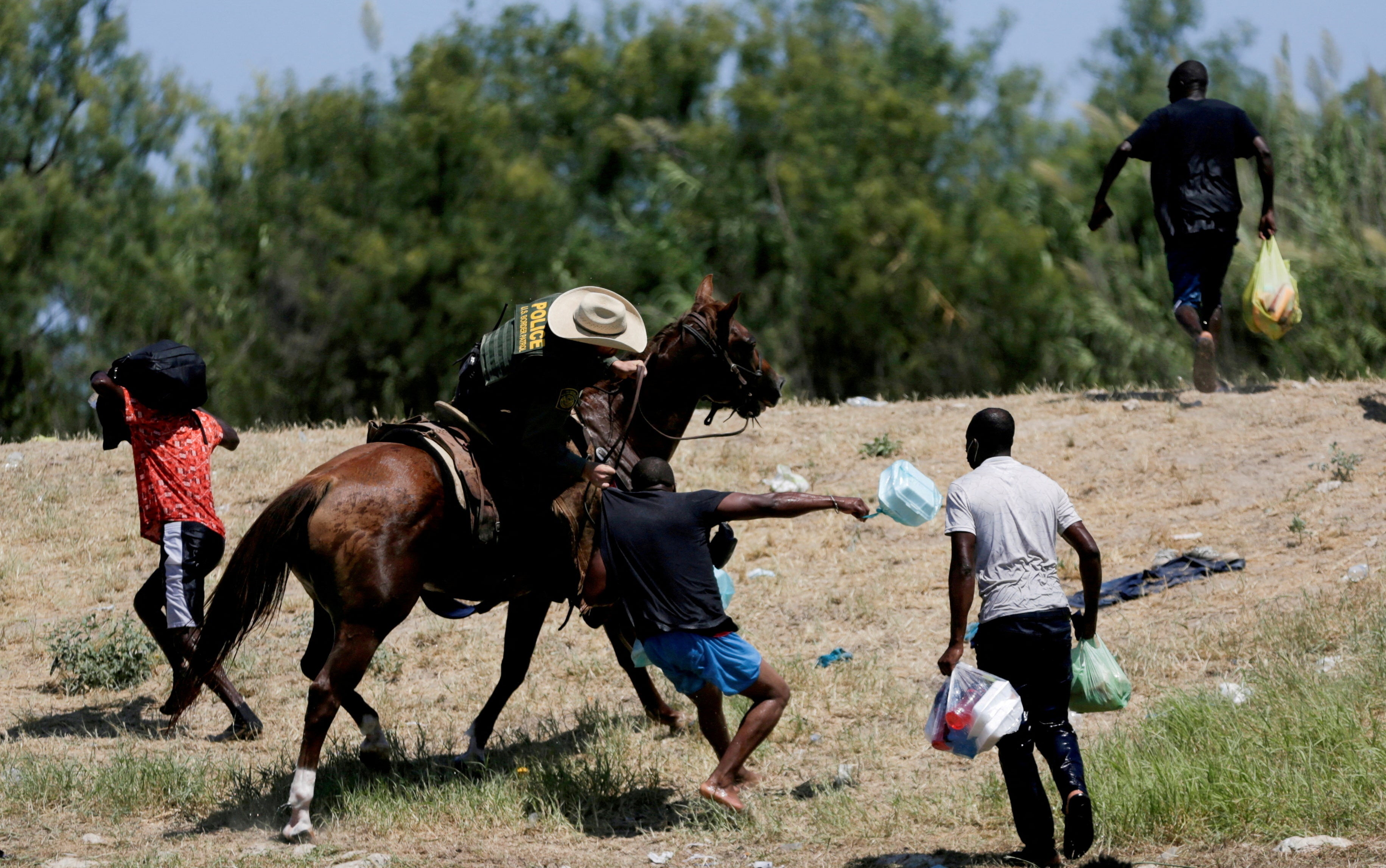 Un agente de la patrulla fronteriza estadounidense agarra la camisa de un migrante que intenta regresar a Estados Unidos a lo largo del Río Grande, después de haber cruzado de Estados Unidos a México para comprar comida, visto desde Ciudad Acuña, en Ciudad Acuña, México 19 de septiembre de 2021