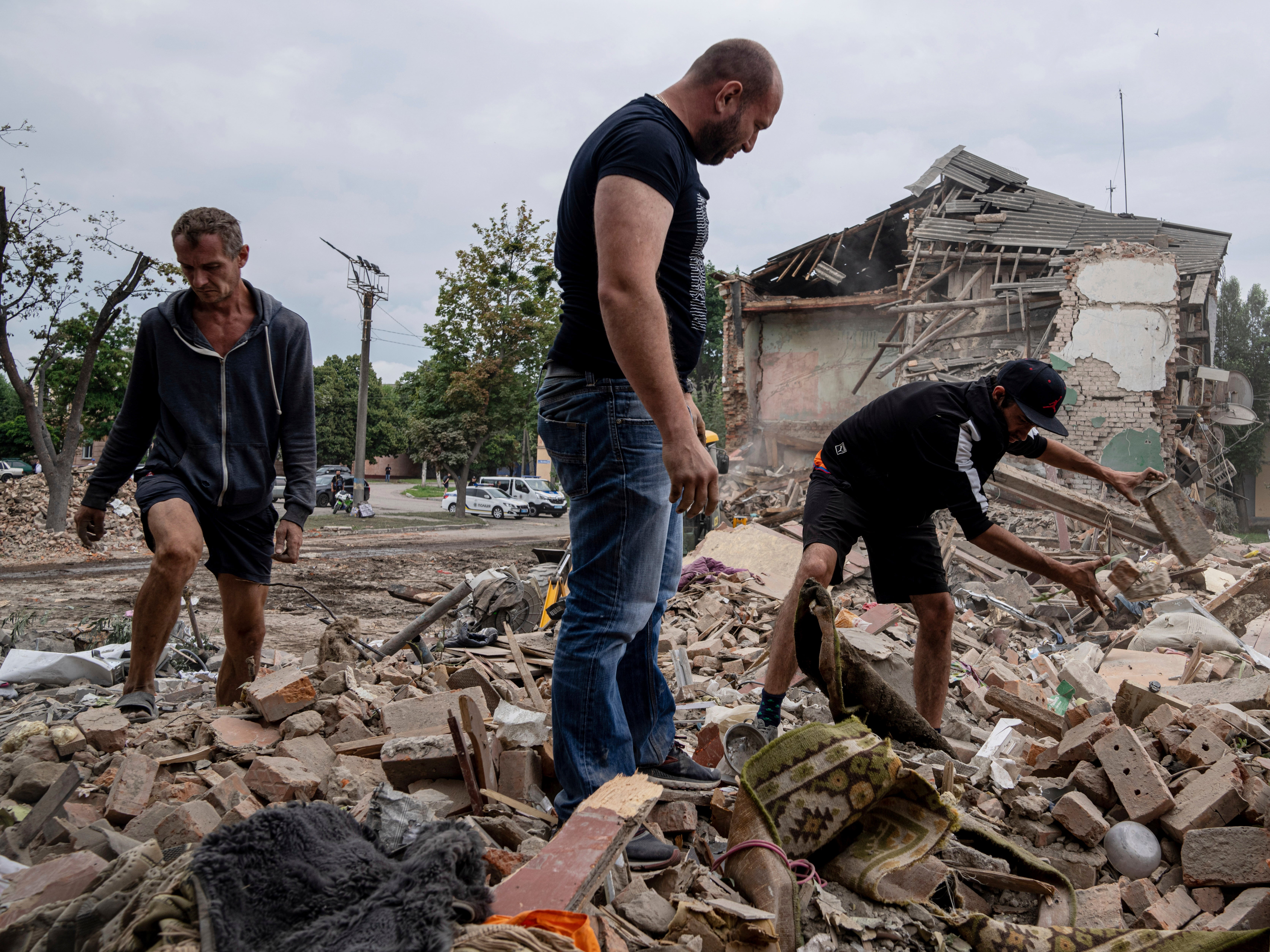 Residentes locales buscan los documentos de su amigo herido entre los escombros de un departamento destruido tras un bombardeo ruso en una zona residencial de Chuhuiv