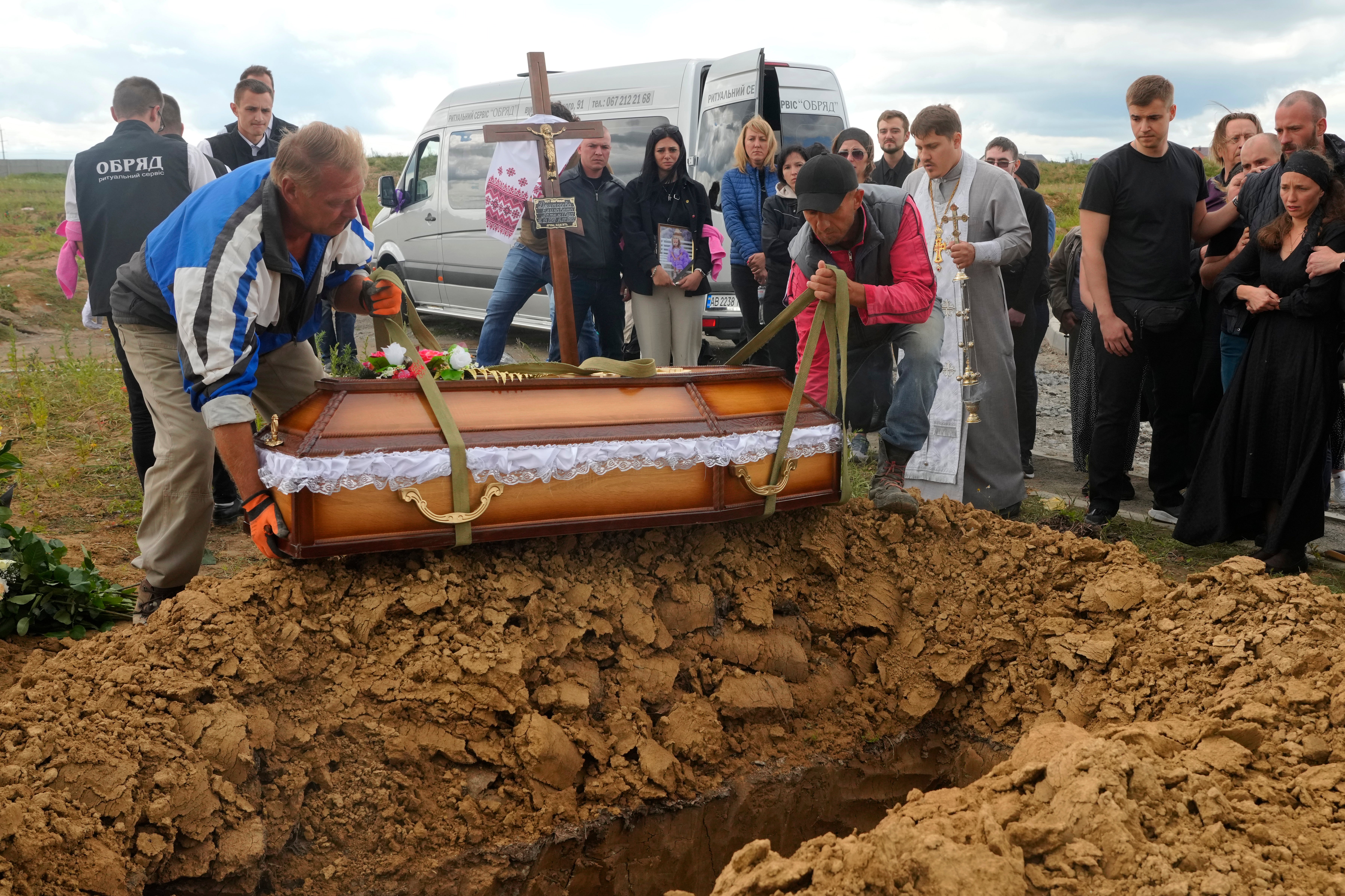 Unos hombres bajan el féretro de Liza, la niña de cuatro años muerta por un ataque ruso, durante una ceremonia fúnebre en Vinnytsia, Ucrania