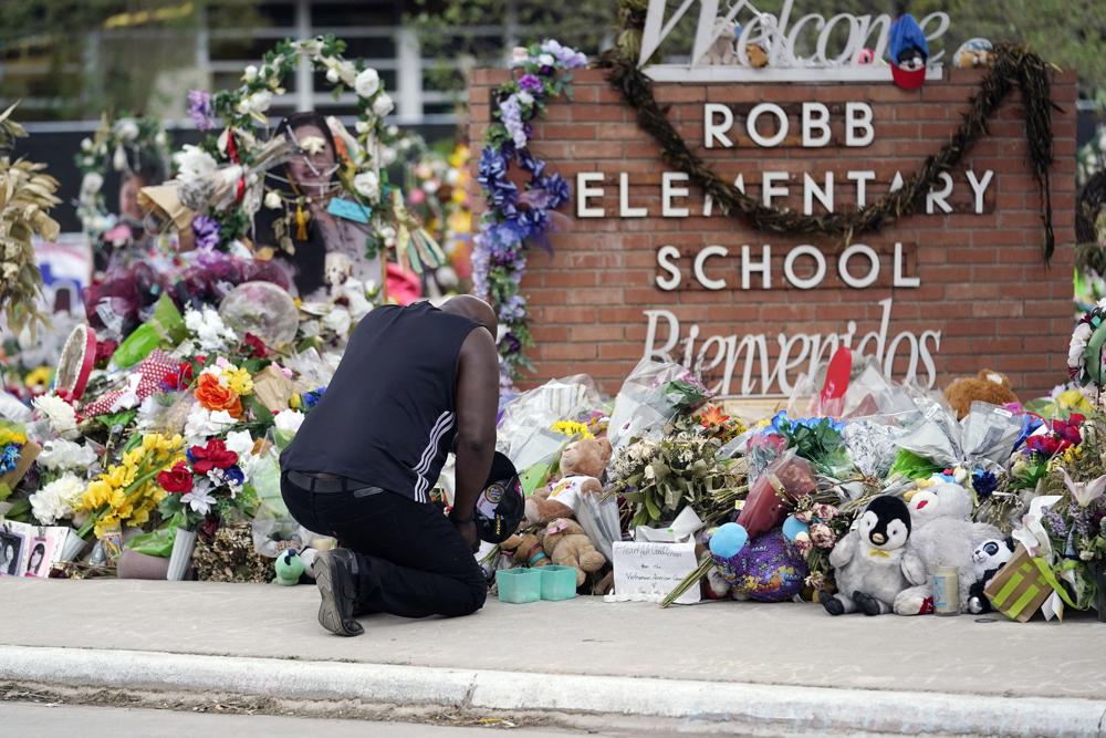Un doliente presenta sus respetos en un monumento conmemorativo frente a la escuela primaria Robb