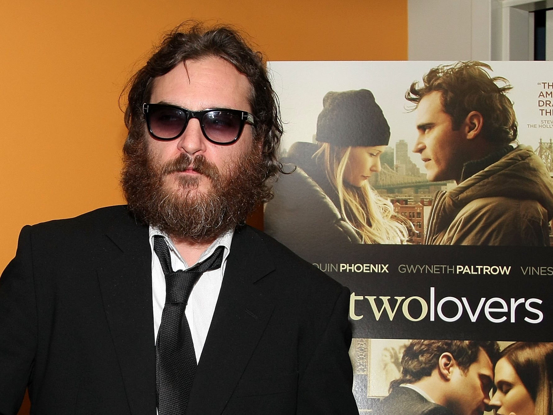 Joaquin Phoenix posa desapasionadamente delante de un poster de su película ‘Two Lovers’ en 2009