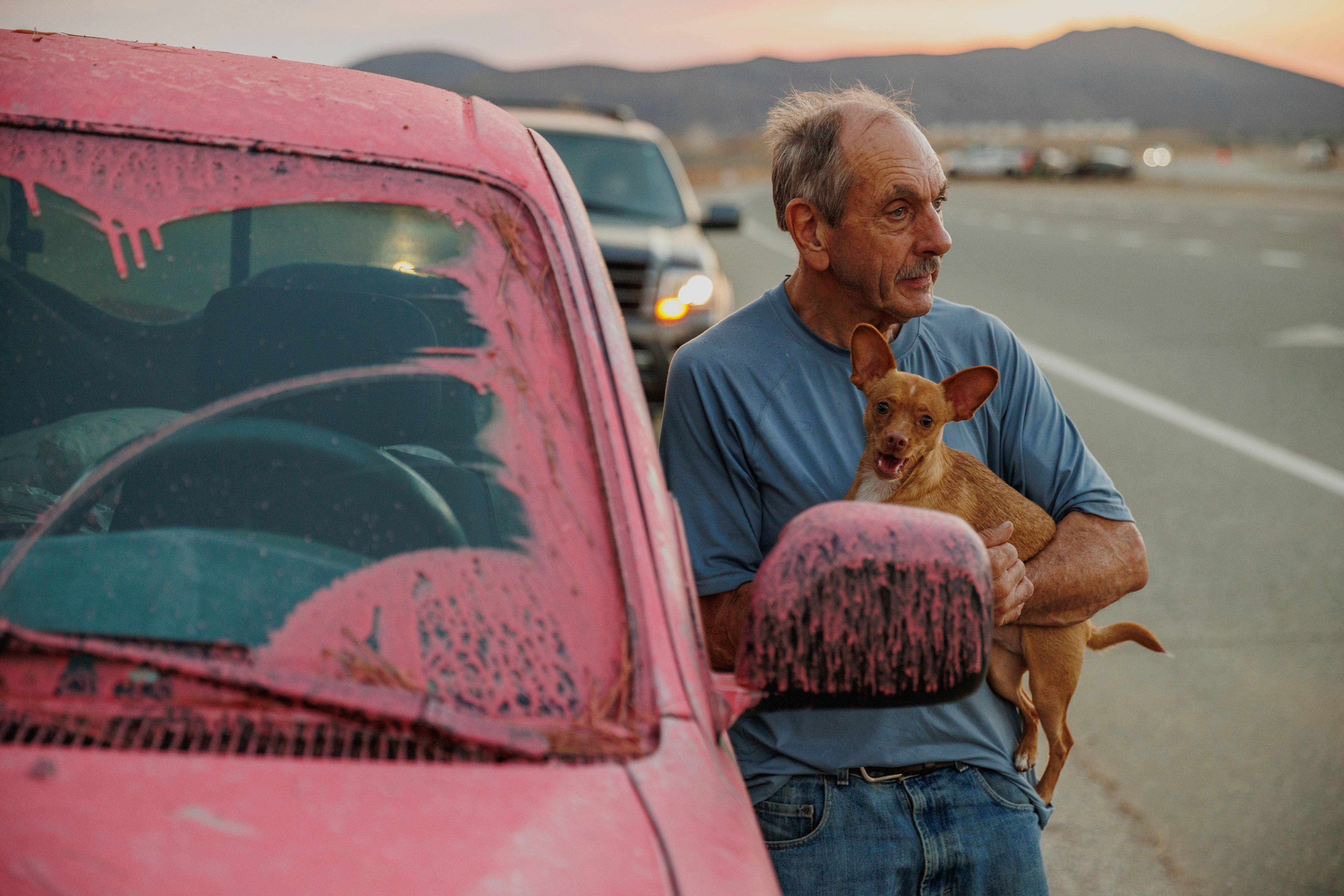 Un hombre sostiene un perro después de evacuar debido al incendio de Fairview en las afueras de Hemet, California