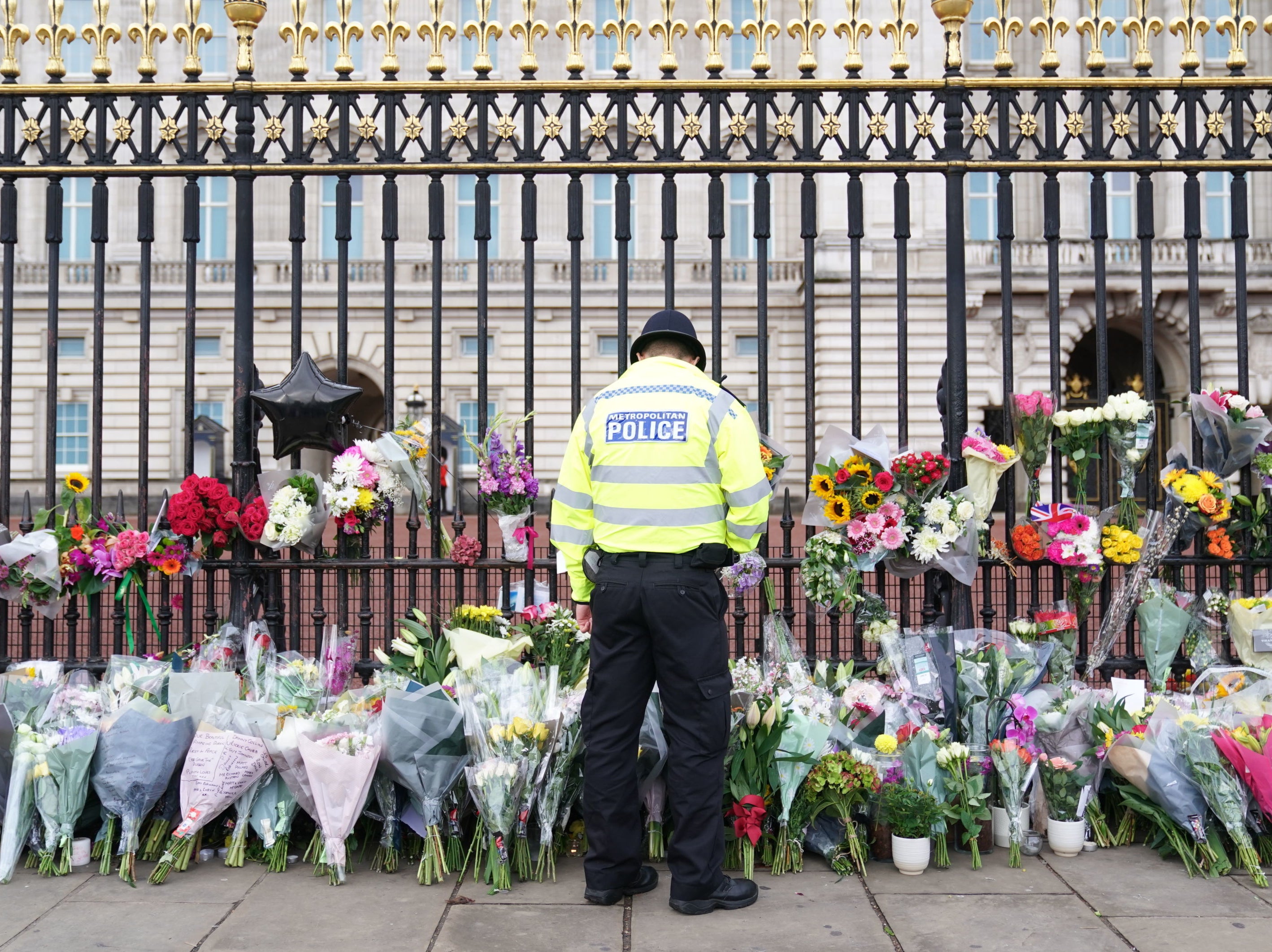 Un agente de policía observa las flores depositadas ante el Palacio de Buckingham tras la muerte de la reina Isabel II el jueves
