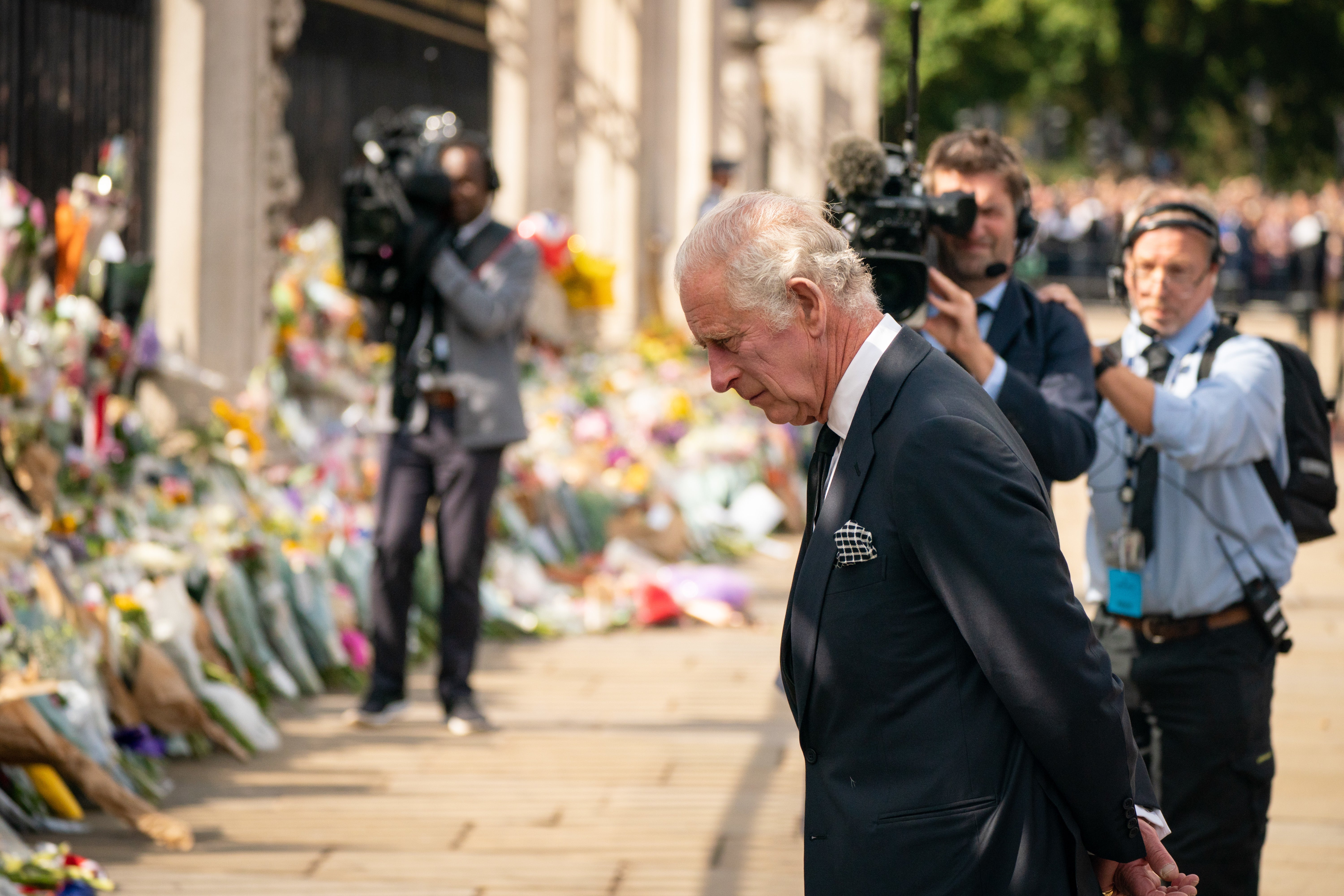 El rey observa las ofrendas florales fuera del Palacio de Buckingham el viernes (Dominic Lipinski/PA)