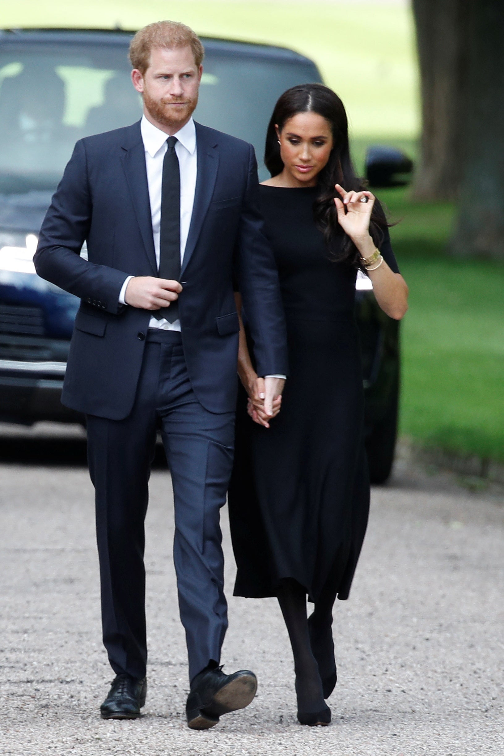 El duque y la duquesa de Sussex caminando fuera del Castillo de Windsor para ver los homenajes florales a la reina
