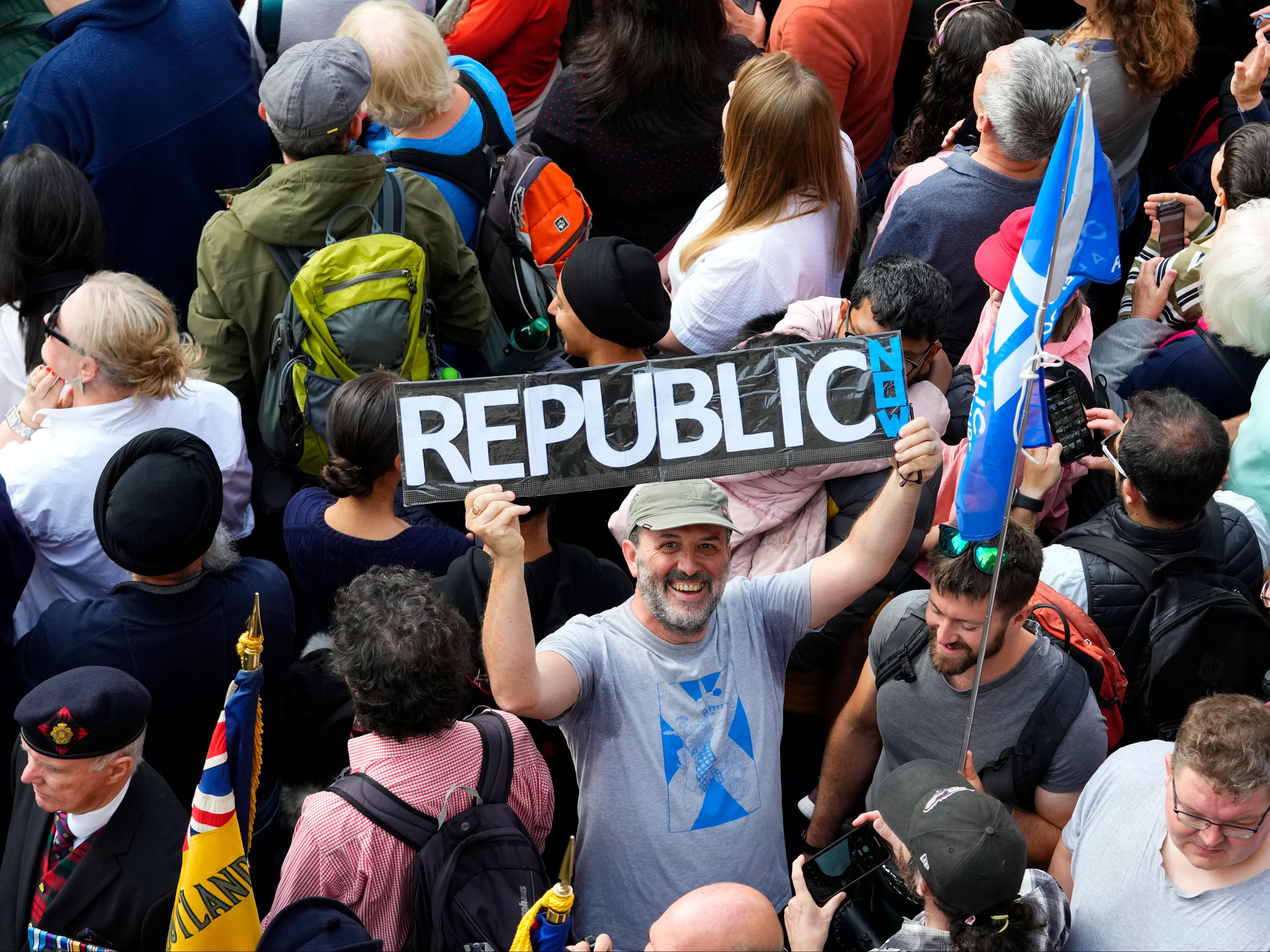 Un hombre sostiene un cartel entre los miembros del público que asisten a una Proclamación pública para anunciar la Ascención del rey Carlos III, fuera de la Catedral de St Giles, en la Royal Mile, en Edimburgo, Escocia, el domingo 11 de septiembre de 2022