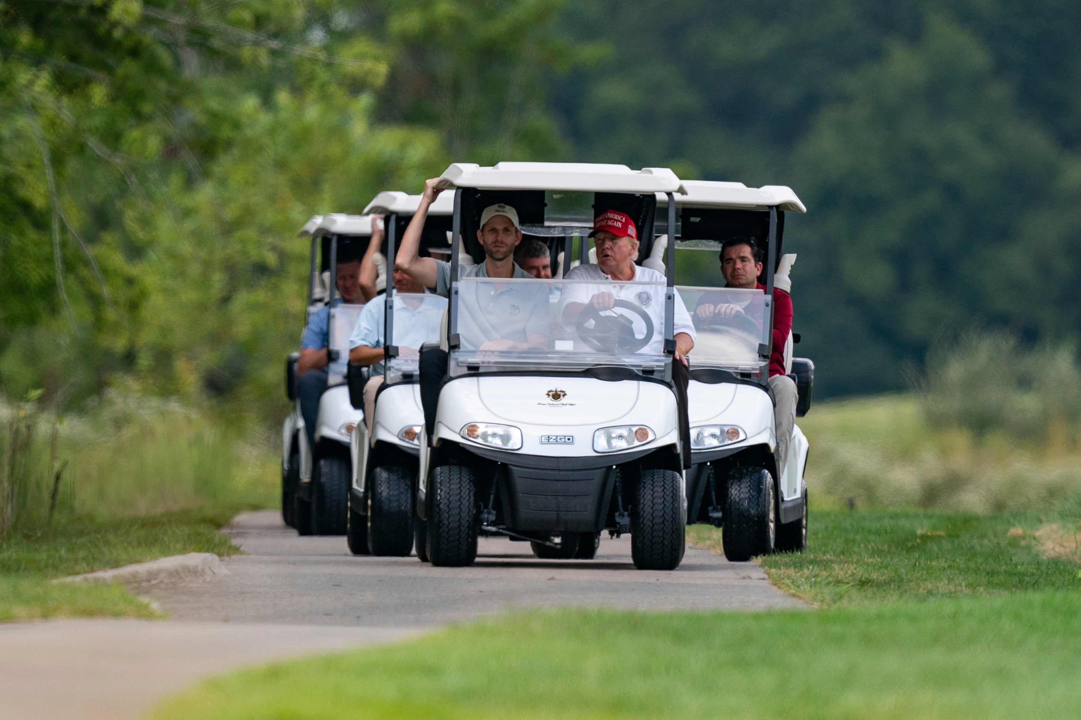 Trump y su hijo Eric forografiados mientras lideran un convoy de carros de golf