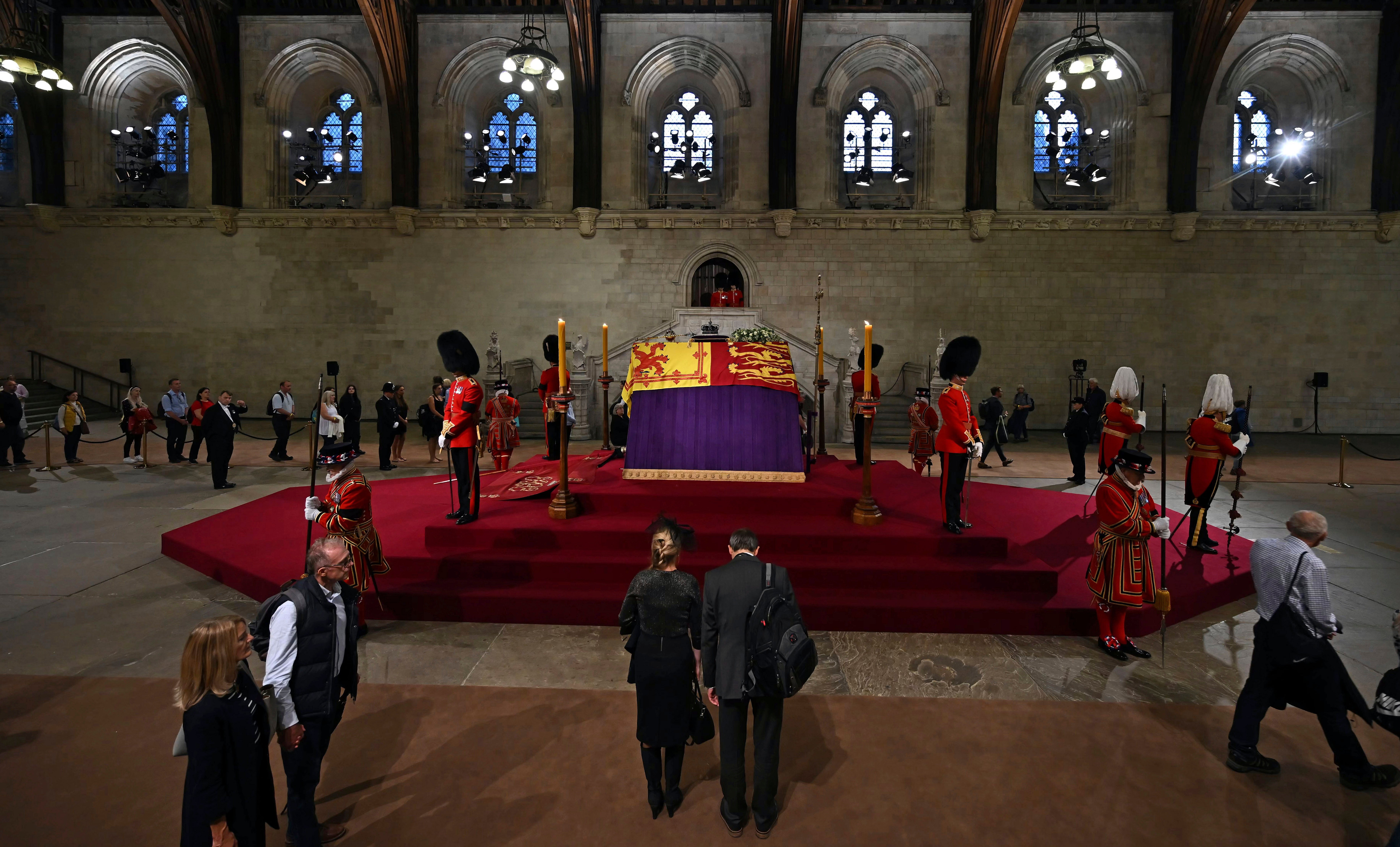 Miembros de la fila del público pasan junto al ataúd de la reina Isabel II