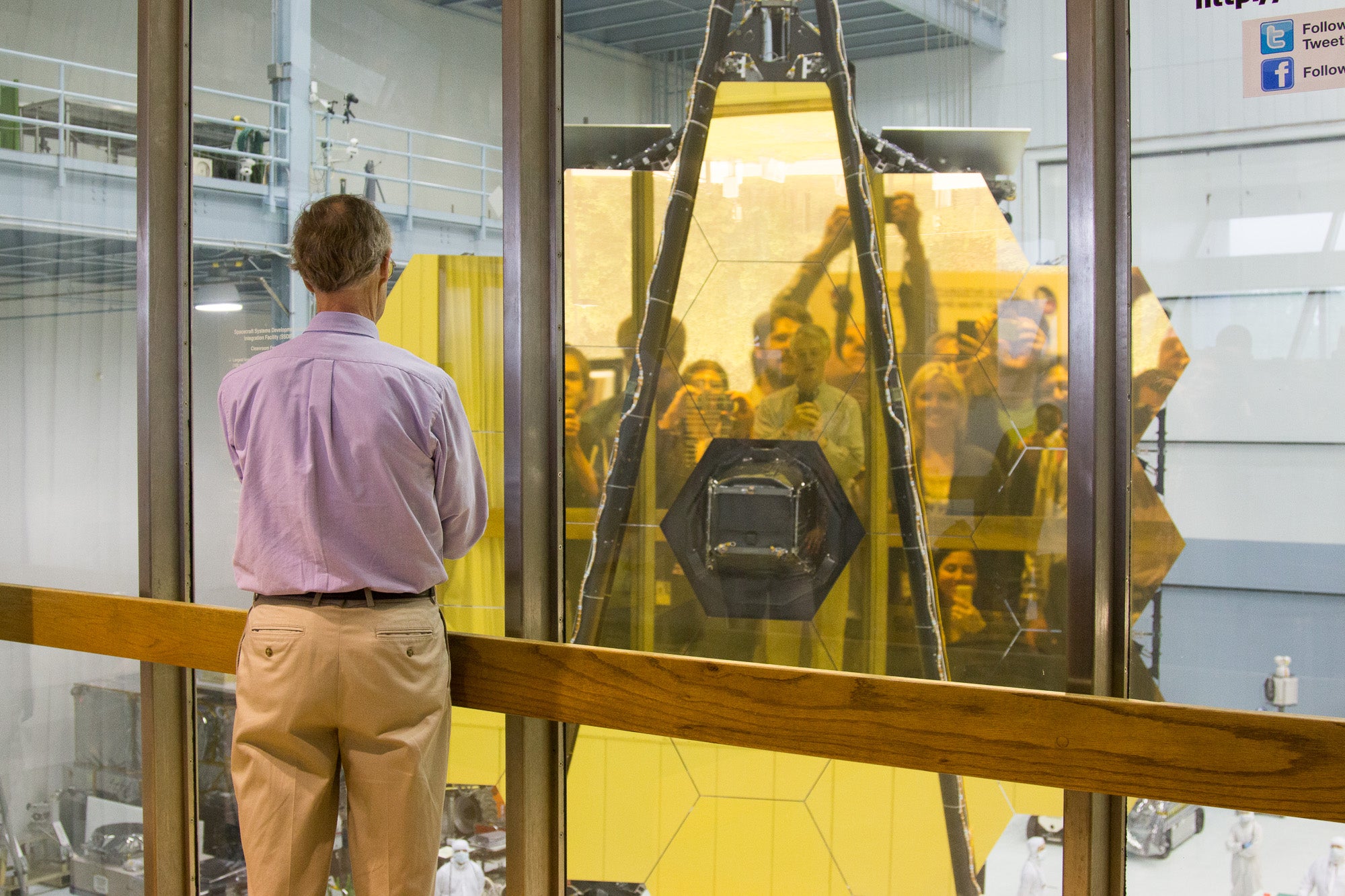 Un grupo de científicos observa su reflejo en el espejo primario del telescopio James Webb en 2017. El telescopio espacial fue lanzado a finales de 2022