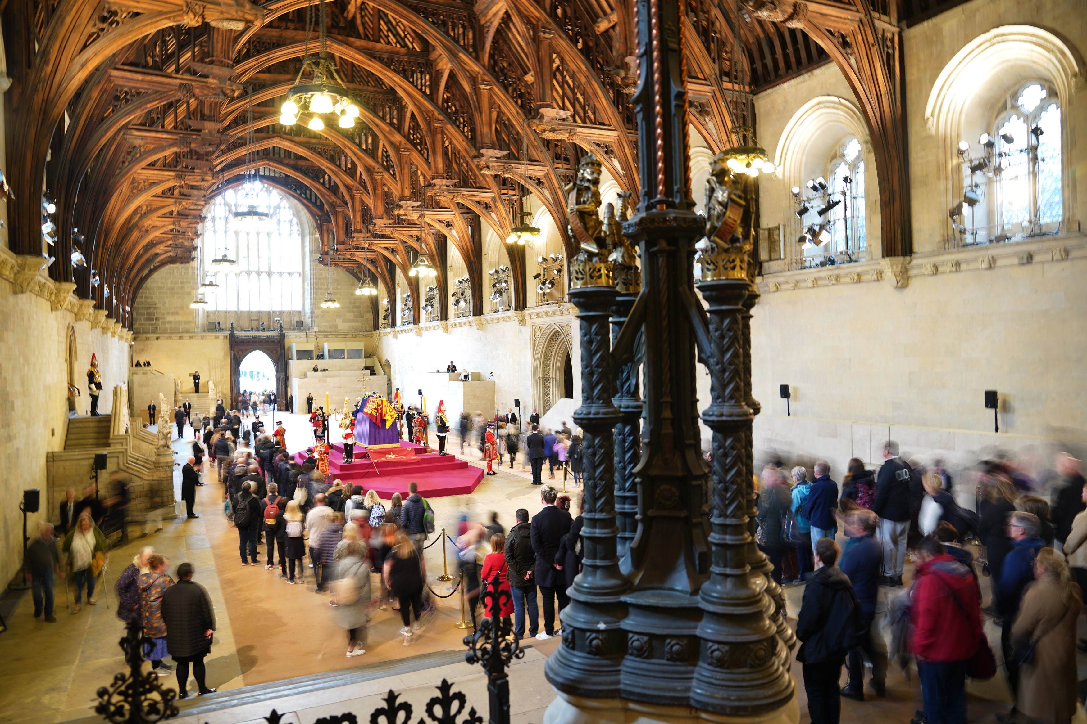 Miembros del público pasan ante el ataúd de la reina Isabel II, cubierto con el estandarte real y la corona imperial de Estado, así como el orbe y el cetro de la soberana