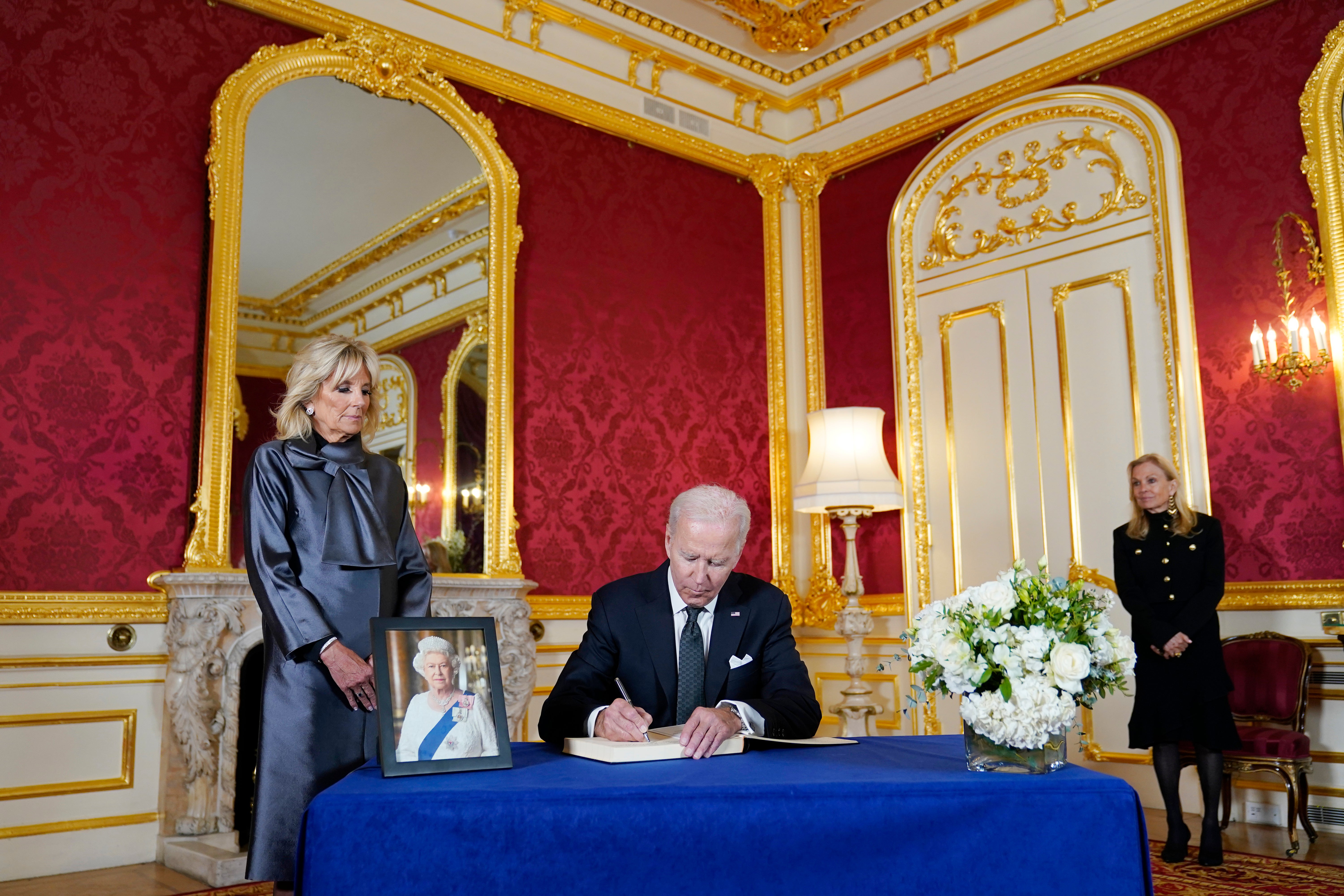 El presidente Biden firma un libro de condolencias para la reina Isabel en Lancaster House, en Londres, mientras la primera dama (izq.) y la embajadora de EE.UU. para el Reino Unido, Jane Hartley, observan