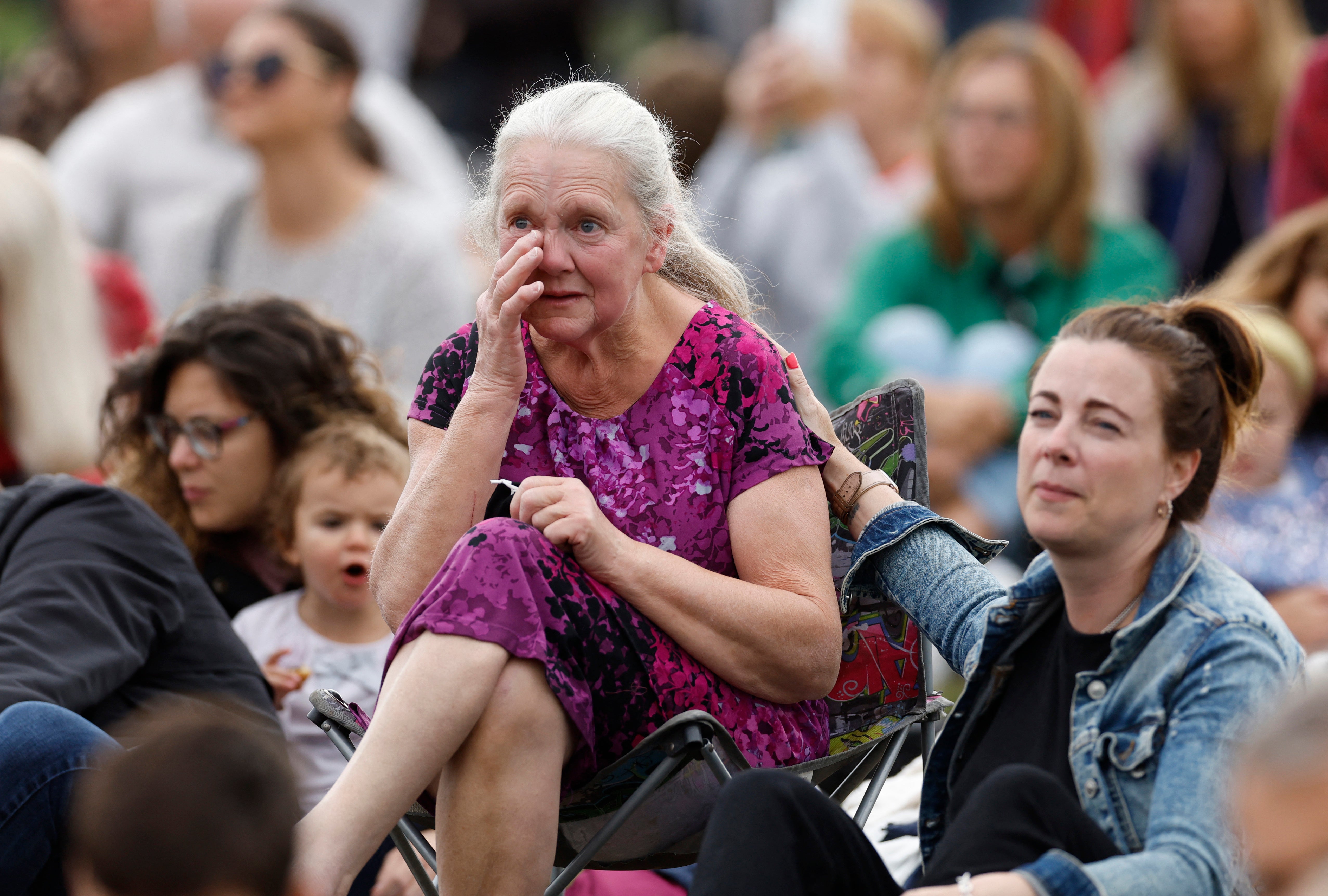 A woman wipes away a tear as mourners gather in Hyde Park for the funeral