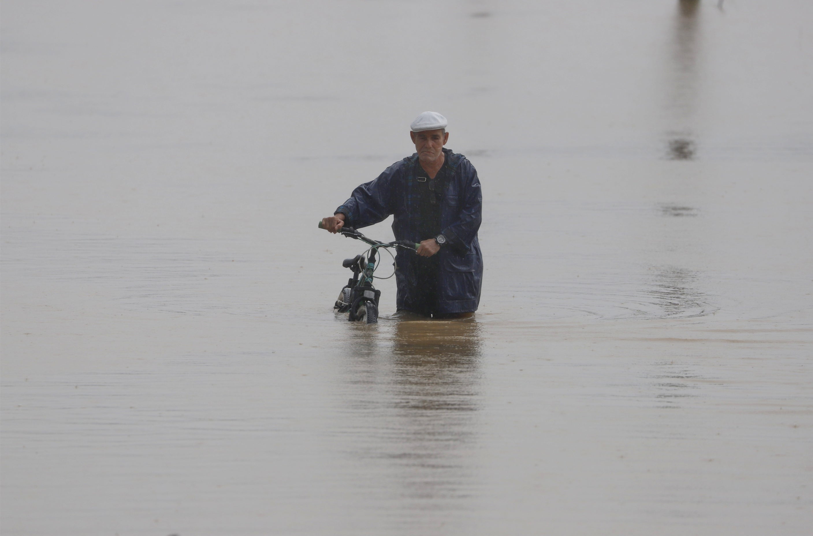Un hombre con una bicicleta camina a través de una calle inundada en Toa Baja, Puerto Rico, tras el paso del huracán Fiona