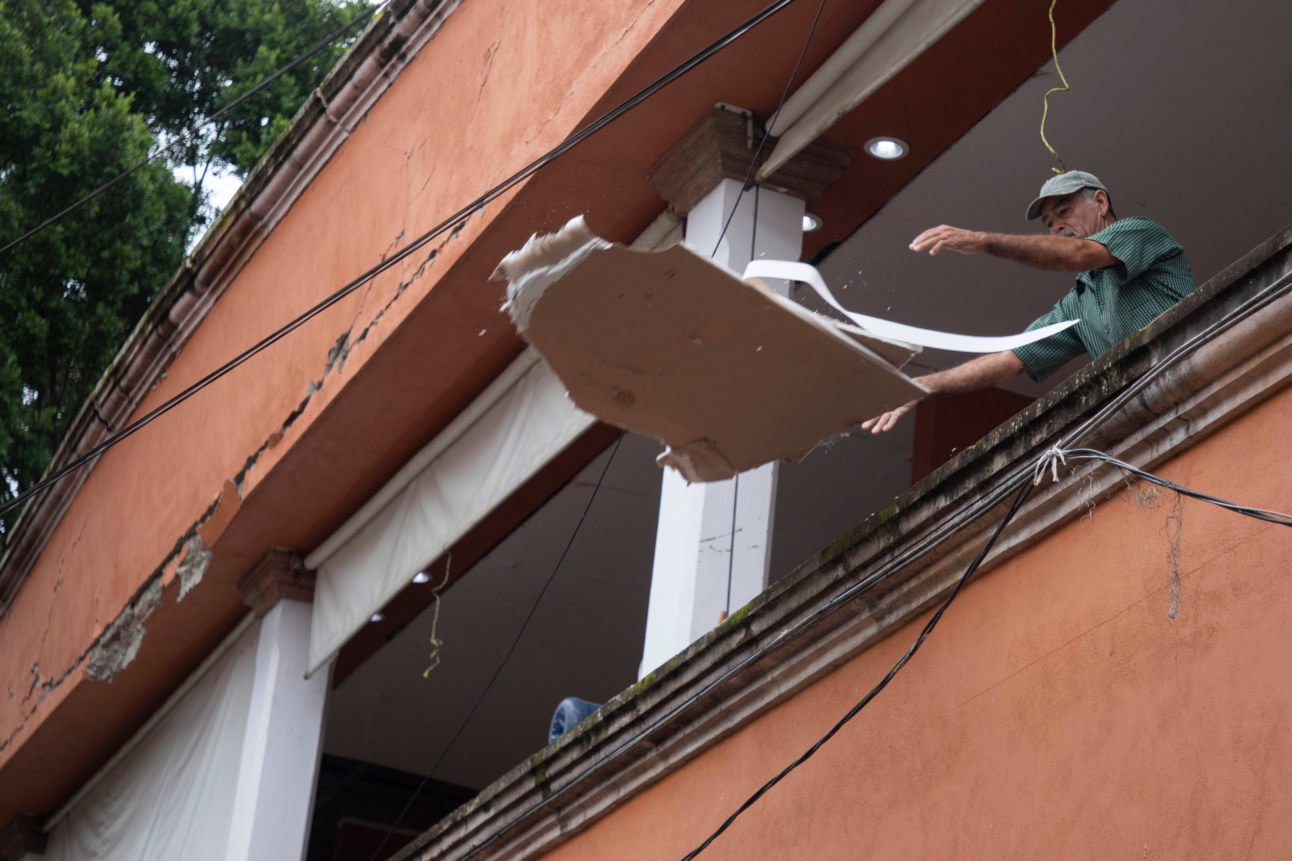 A resident tosses materials from a building damaged by the previous day's earthquake in Coalcoman, Michoacan state, Mexico, Tuesday, Sept. 20, 2022