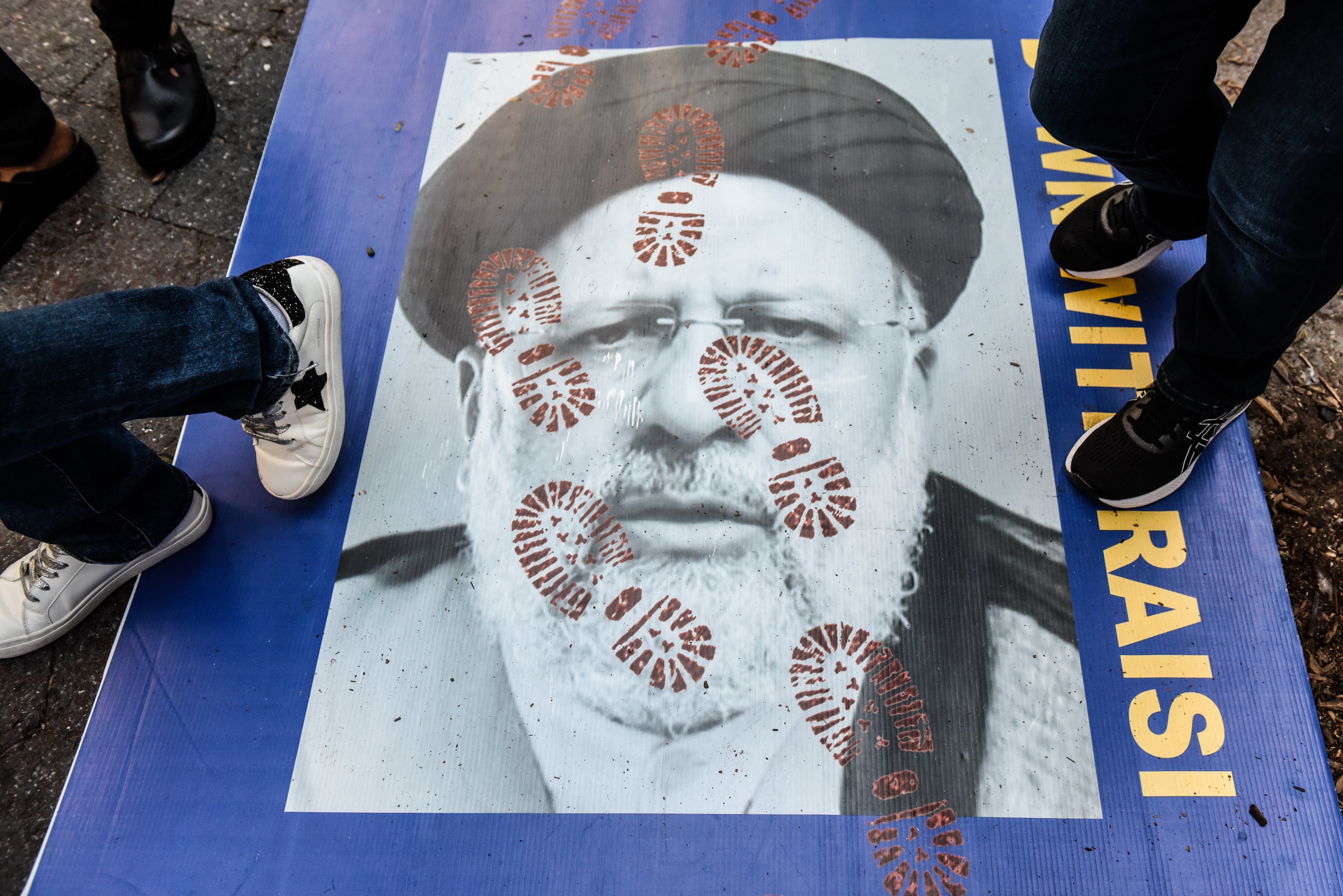 La gente pisa un cartel del presidente iraní Ebrahim Raisi mientras participa en una protesta ante las Naciones Unidas