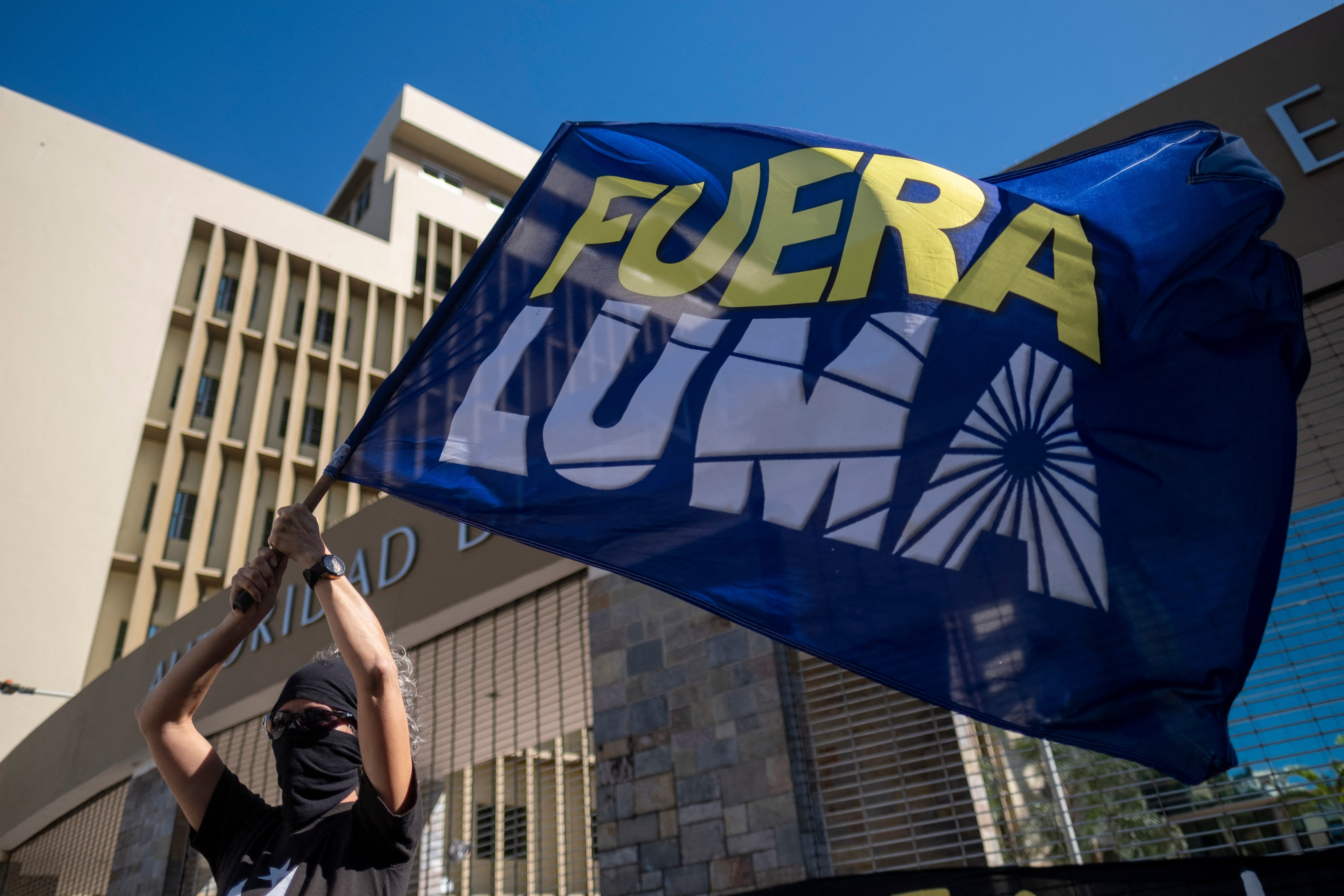 Una mujer agita una bandera en la que se lee “Fuera LUMA” durante una protesta frente a la sede de LUMA Energy