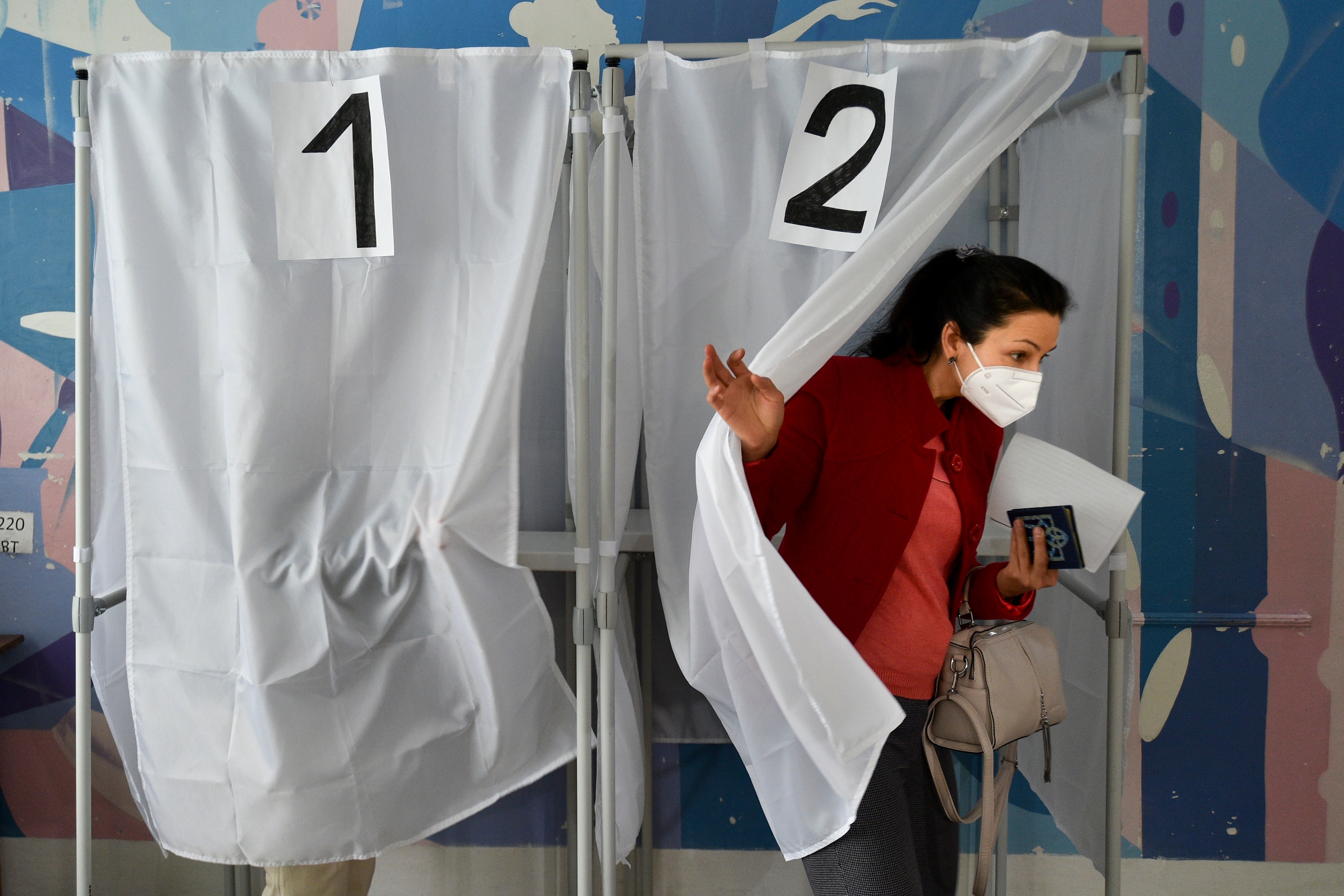 Una mujer sostiene su boleta mientras sale de una cabina de votación en un colegio electoral durante el referéndum en Melitopol