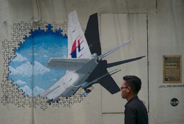 <p>A man walks pasts a mural representing the missing Malaysia Airlines flight MH370 in an alley in Shah Alam, on the outskirts of Kuala Lumpu</p>