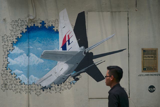 <p>A man walks pasts a mural representing the missing Malaysia Airlines flight MH370 in an alley in Shah Alam, on the outskirts of Kuala Lumpu</p>