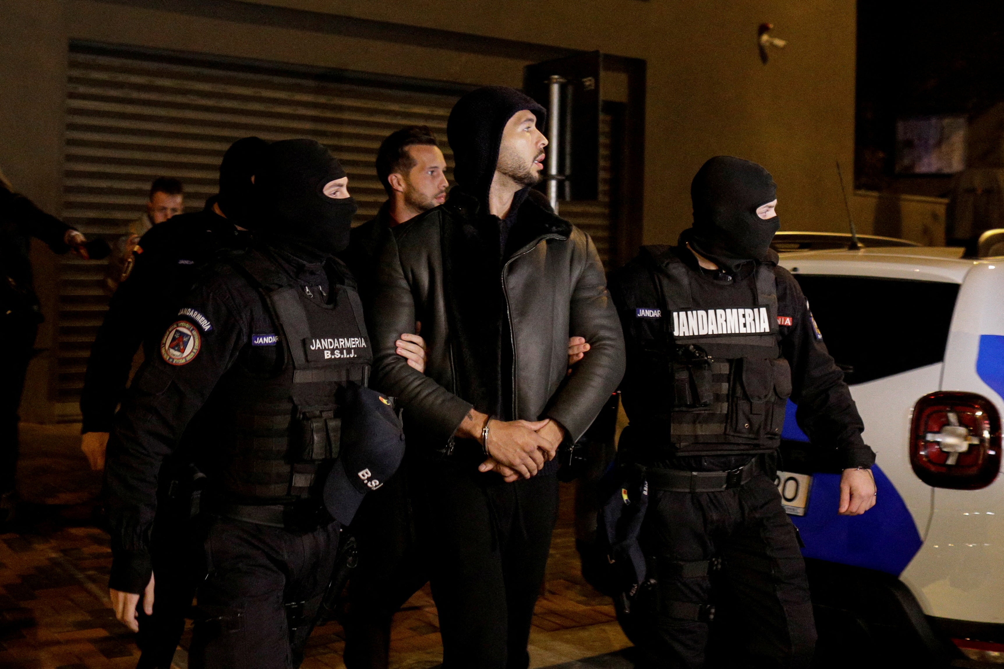 Andrew Tate y Tristan Tate son escoltados por agentes de policía a las puertas de la sede de la DIICOT (Dirección para la Investigación de la Delincuencia Organizada y el Terrorismo de Bucarest) tras permanecer 24 horas detenidos