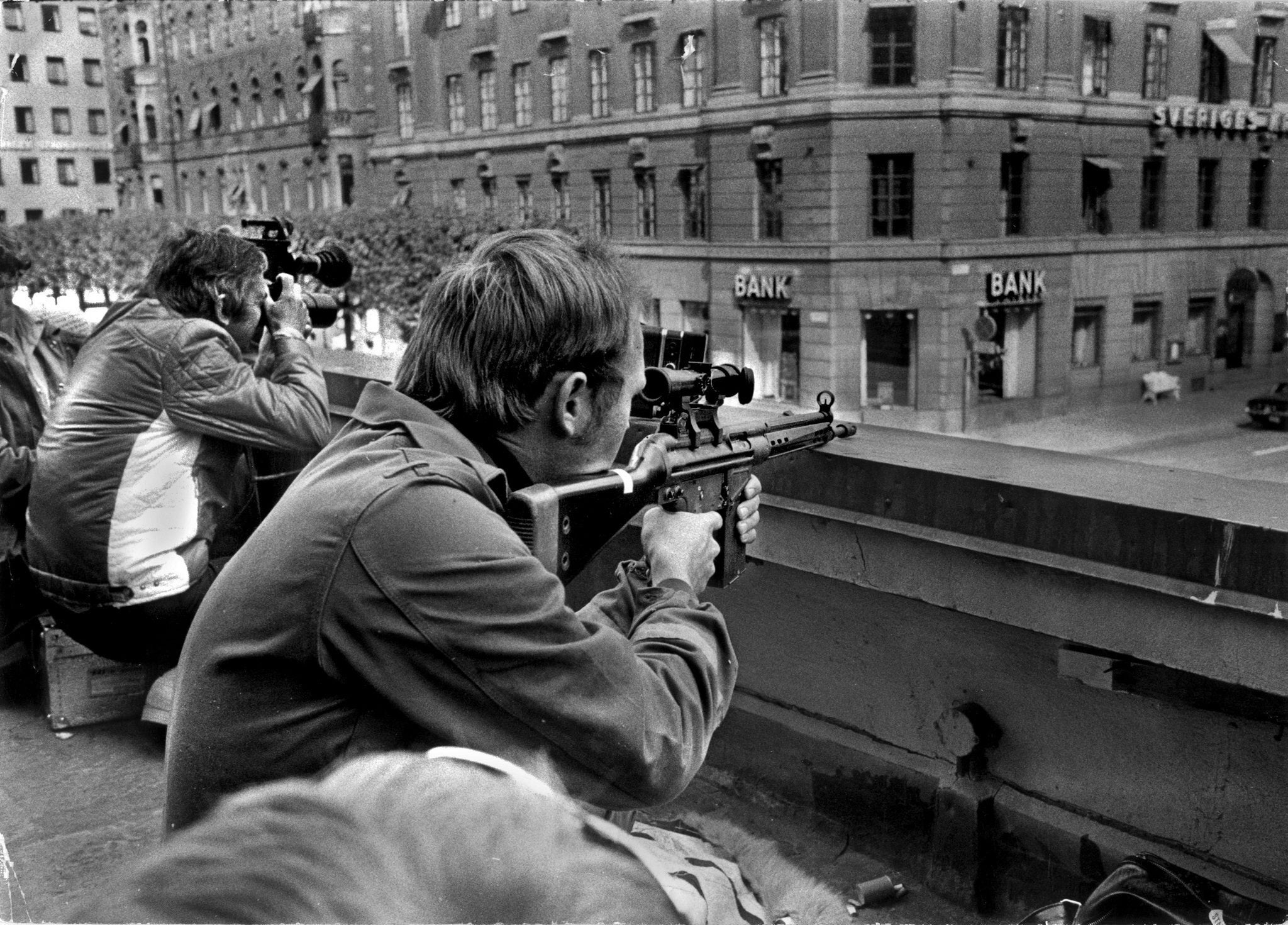 Fotógrafos de prensa y francotiradores de la policía colocados uno al lado del otro en un tejado frente al banco Kreditbanken, en la plaza Norrmalmstorg de Estocolmo, el 24 de agosto de 1973. Una de las rehenes, Kristin Enmark, declaró que pensó más que podría morir a manos de la policía que de los captores
