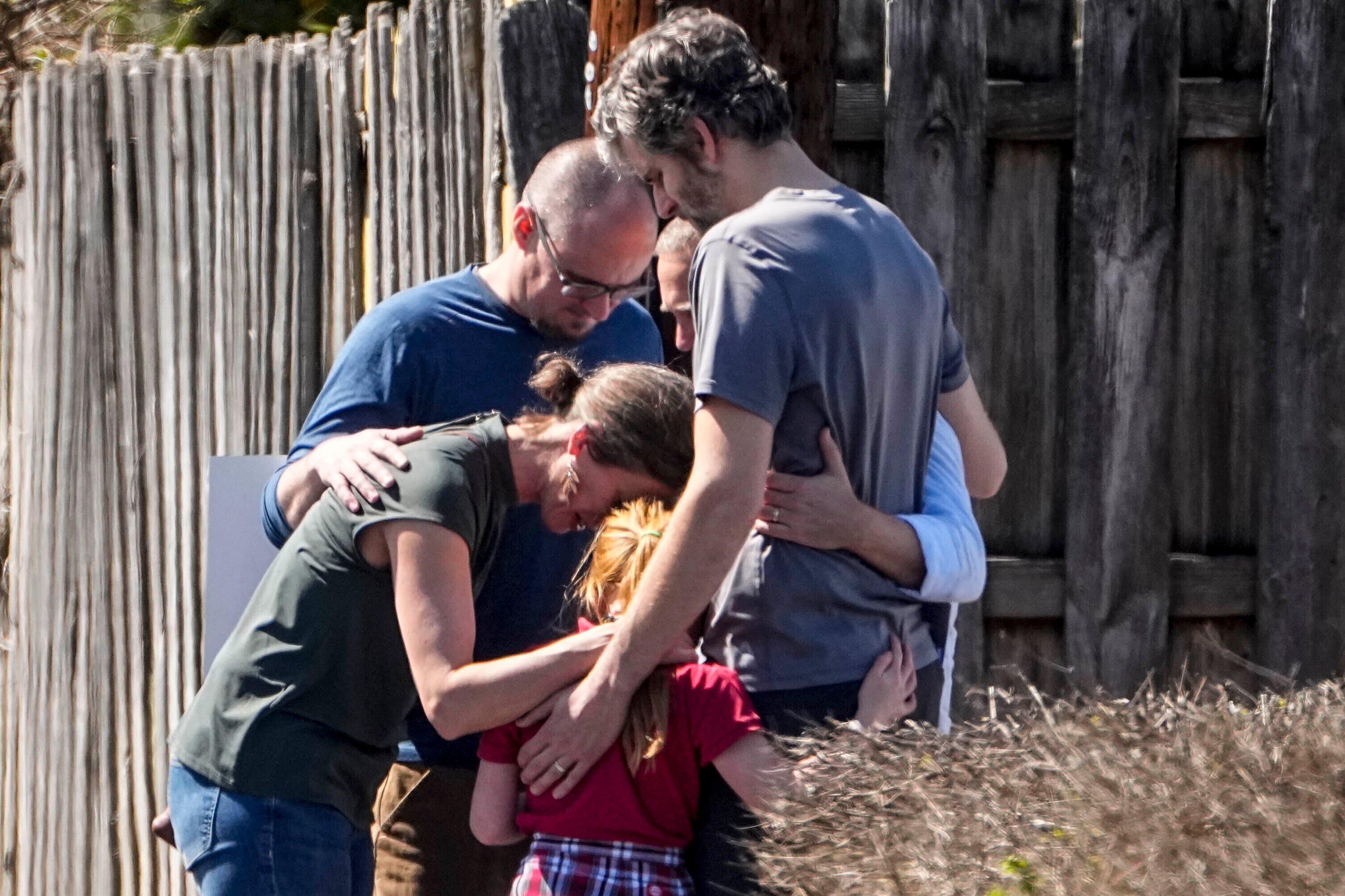 A group prays with a child outside the reunification center at the Woodmont Baptist church after a school shooting, Monday, March 27, 2023, in Nashville, Tenn.