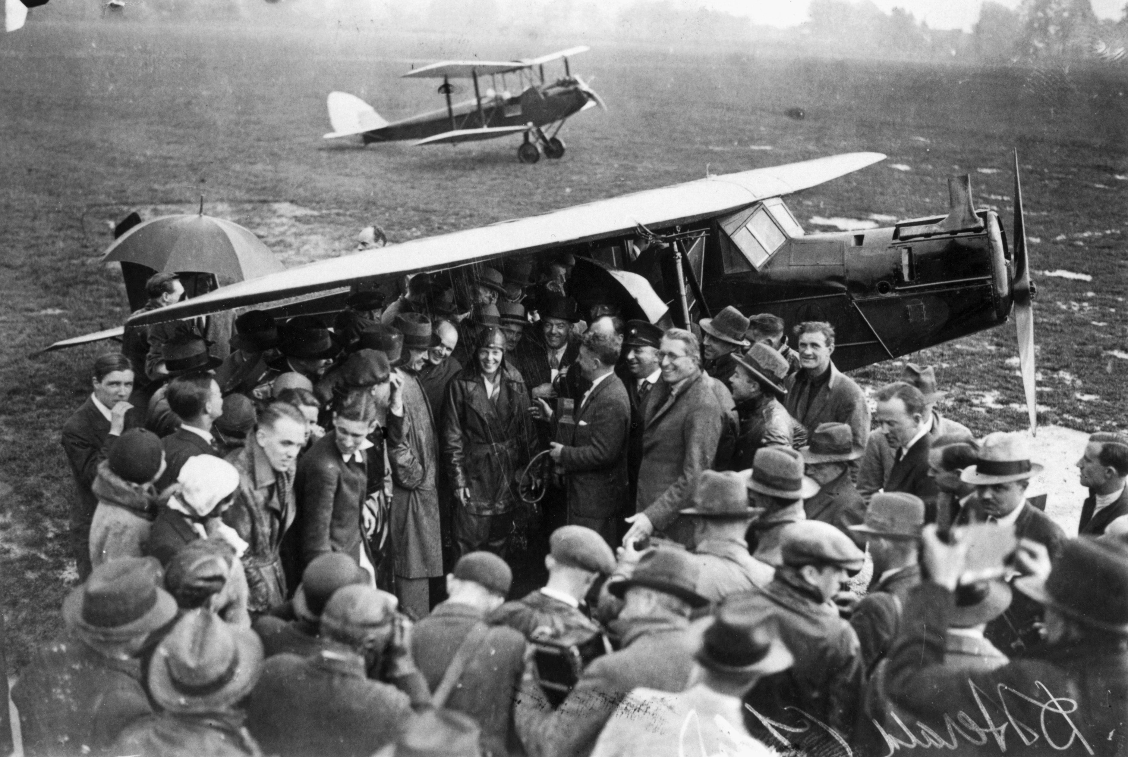 La aviadora estadounidense Amelia Earhart (1898-1937), en el centro, rodeada de una multitud de simpatizantes y periodistas a su llegada al aeródromo de Hanworth tras cruzar el Atlántico.