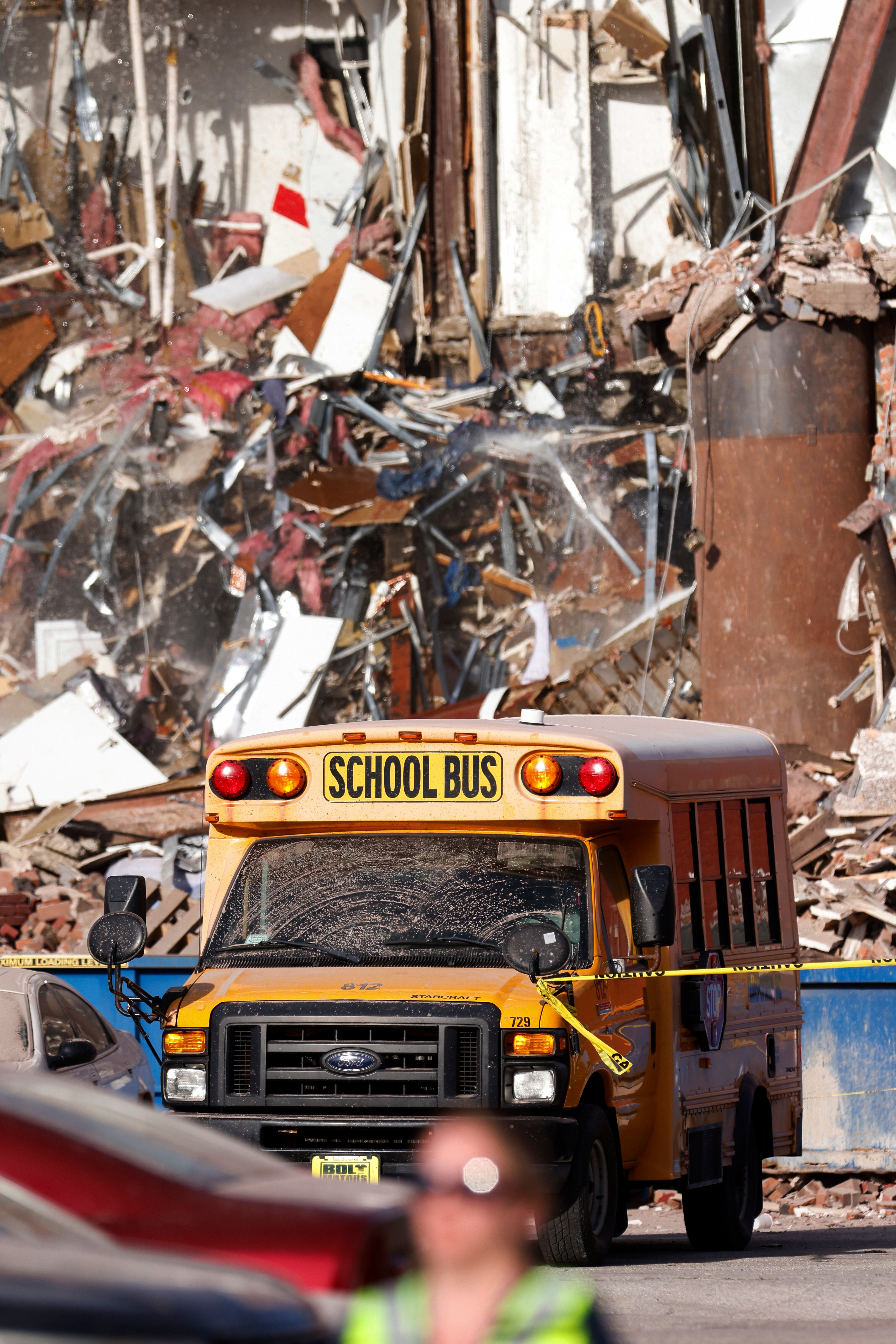 Un camión escolar atraviesa los escombros después del colapso de un edificio el domingo