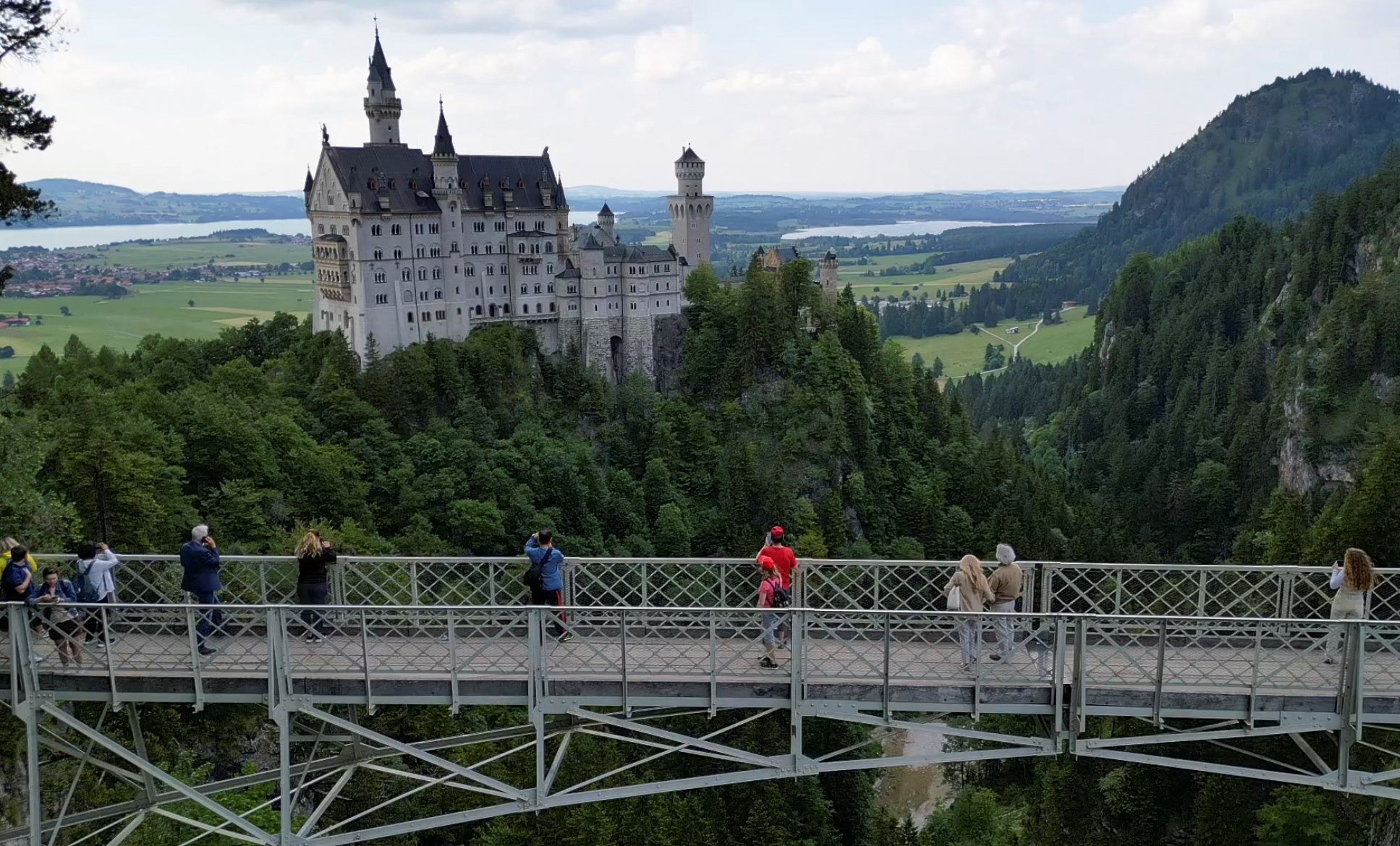 Un grupo de turistas contempla la vista del castillo de Neuschwanstein desde el puente de Marienbrücke