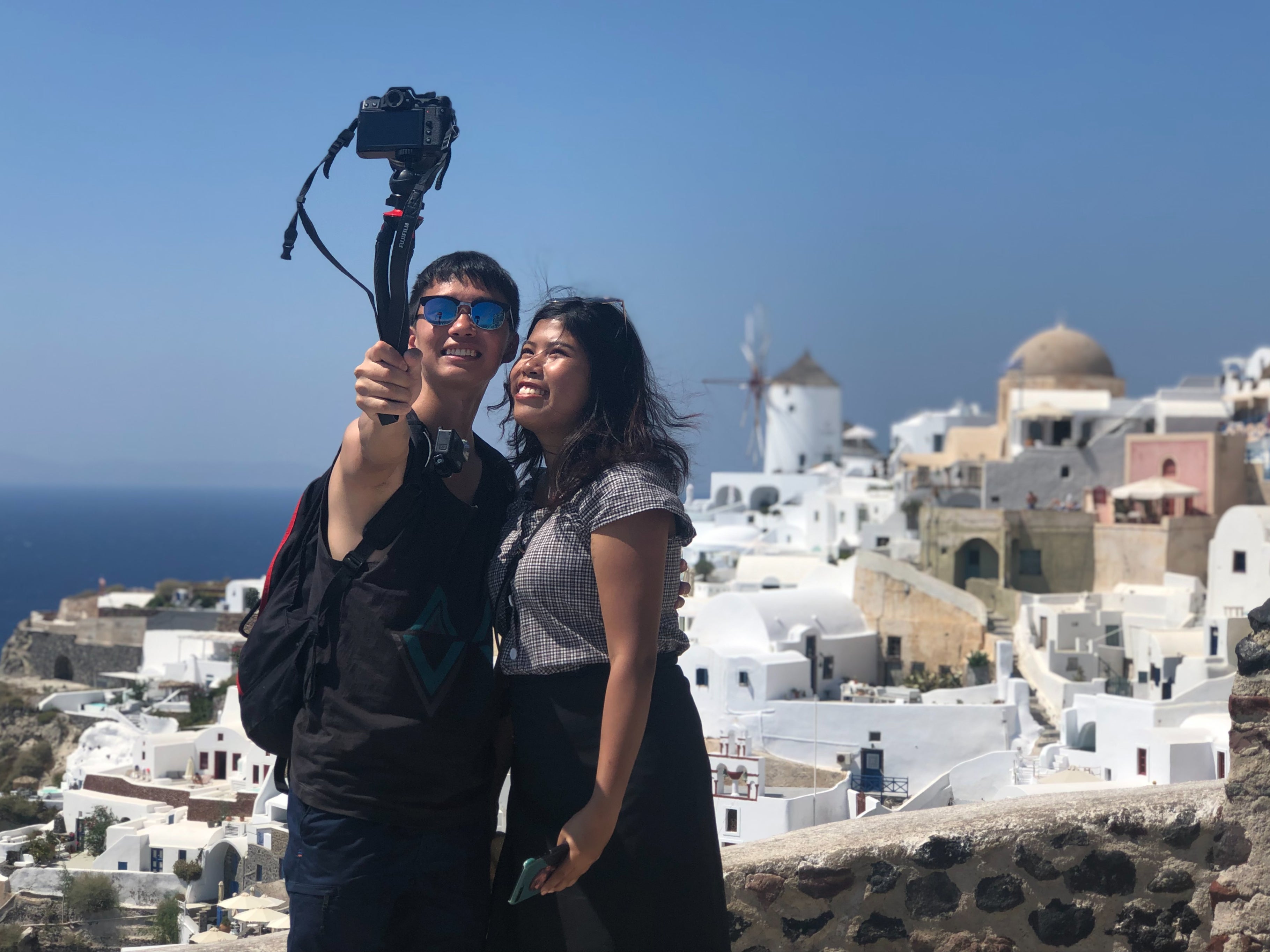 Pareja tomándose un selfi desde lo alto de un mirador en Santorini, Grecia