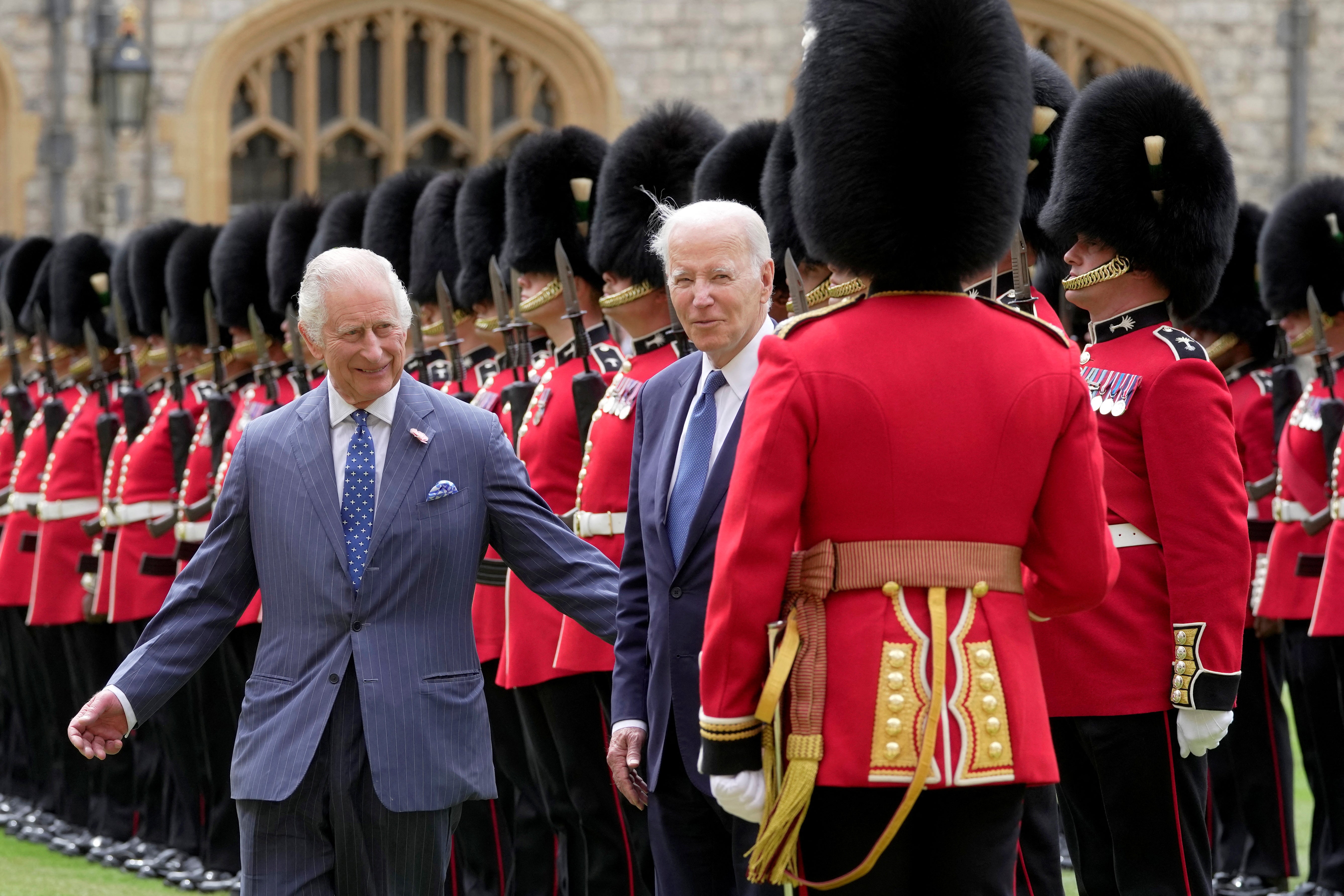 El rey Carlos abre el paso al presidente Biden mientras el mandatario estadounidense charla con un guardia