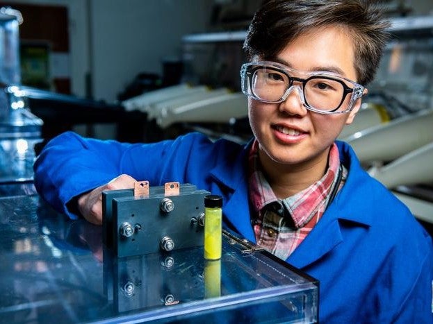 El investigador de baterías de flujo Ruozhu Feng posa con los ingredientes de una batería de energía de red de larga duración