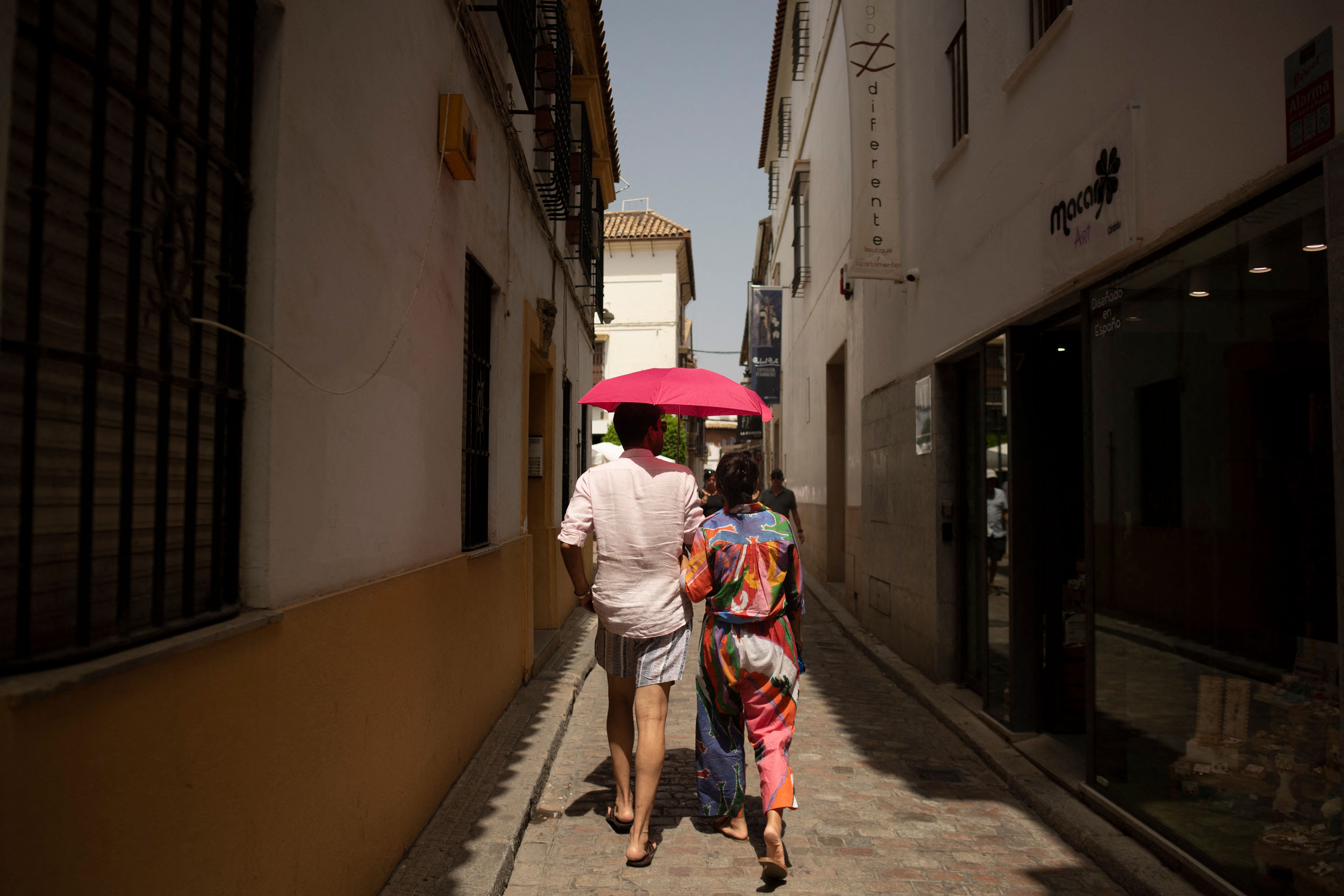 Turistas utilizan una sombrilla para protegerse del sol durante una ola de calor en Córdoba, España