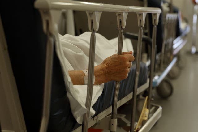 Un paciente se agarra con la mano a los barrotes de su cama mientras espera tratamiento en el pasillo del servicio de urgencias del Hospital de Arcachon en Arcachon, suroeste de Francia, el 10 de agosto de 2023.