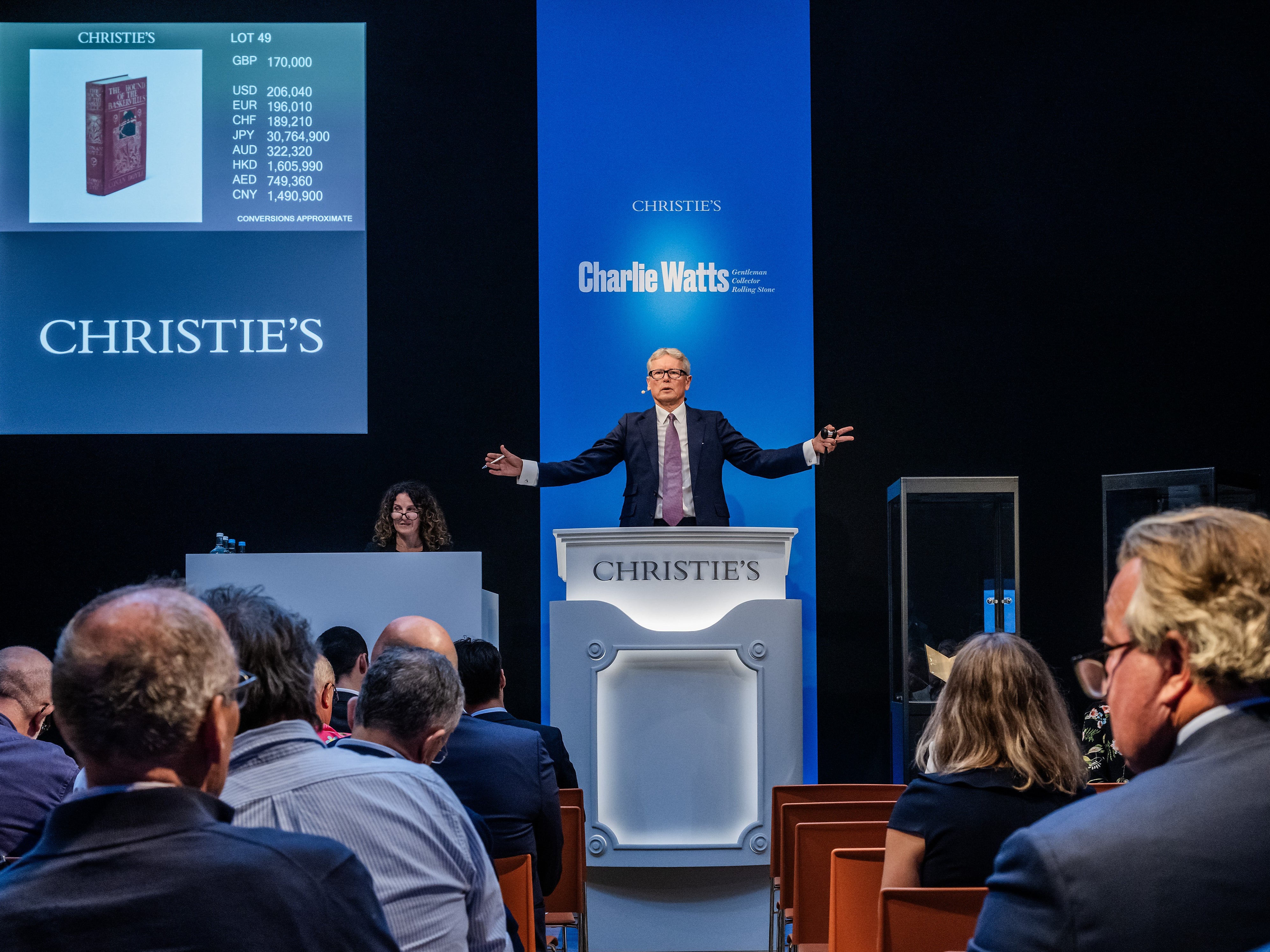 Un subastador de Christie's acepta ofertas por una primera edición de "El perro de los Baskerville" de Sir Arthur Conan Doyle, propiedad del fallecido baterista de los Rolling Stones, Charlie Watts.