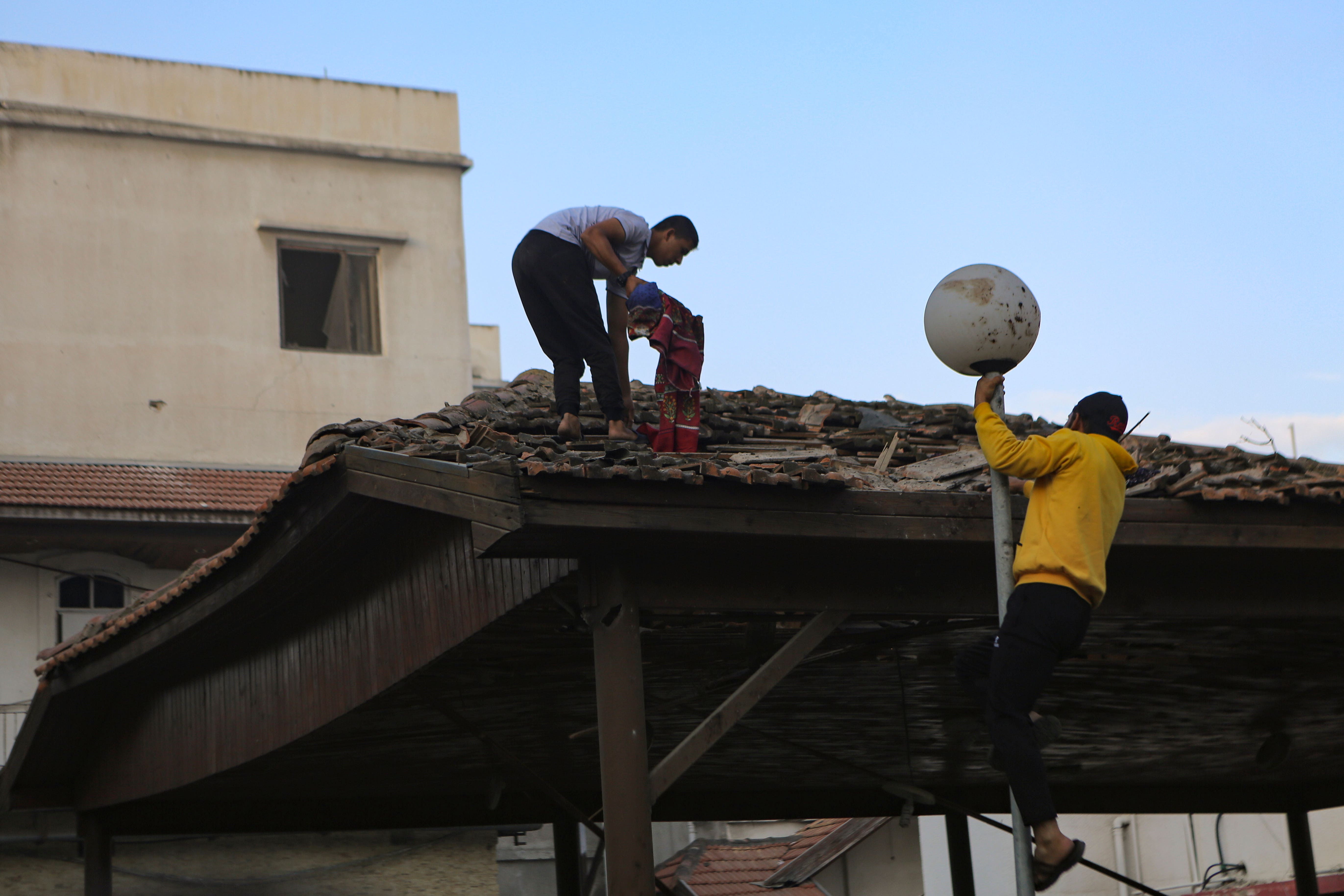 Palestinos inspeccionan daños en el hospital Al Ahli, en la ciudad de Gaza, el miércoles