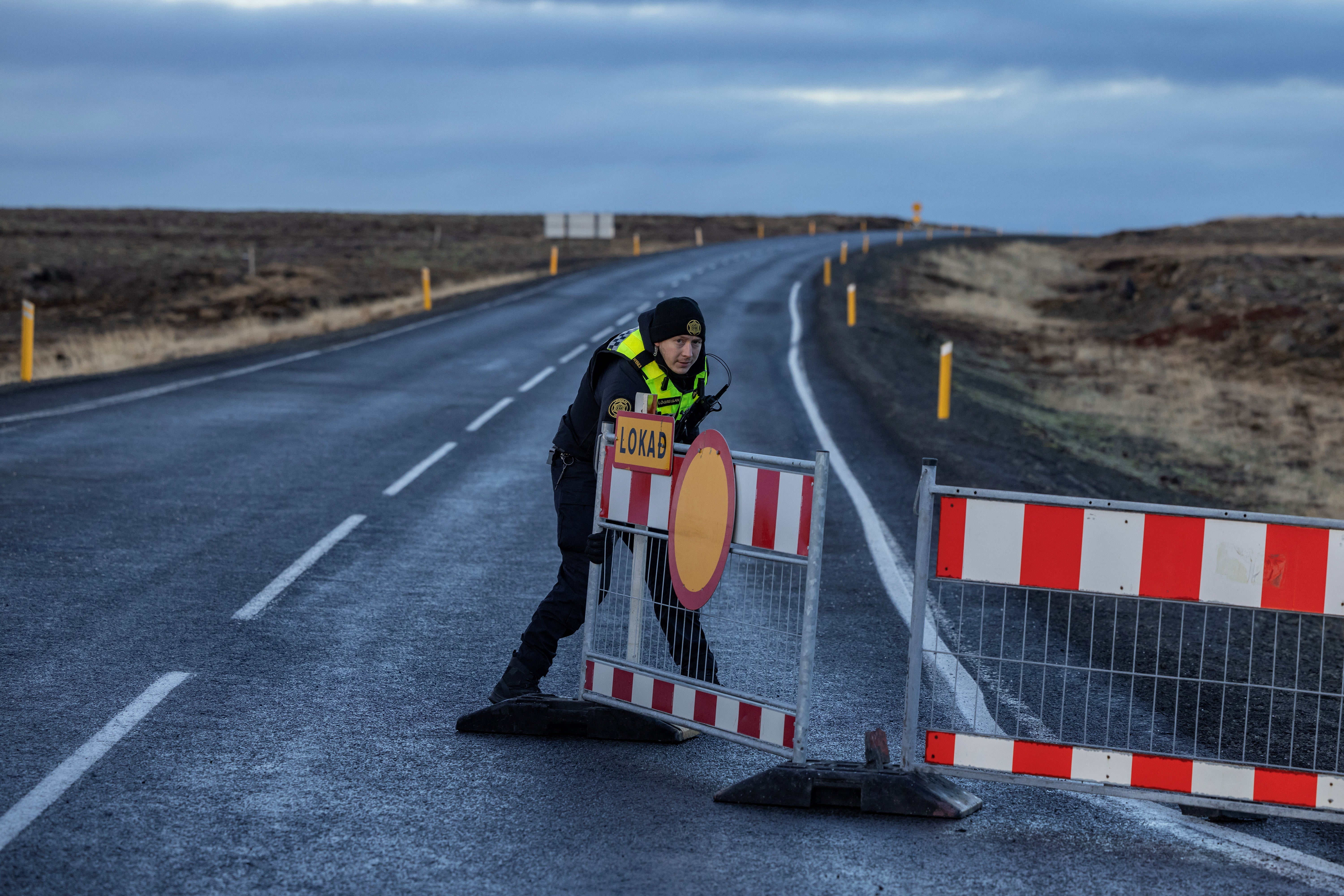 Un agente de policía coloca una barrera para bloquear la carretera que conduce a la ciudad pesquera de Grindavik.