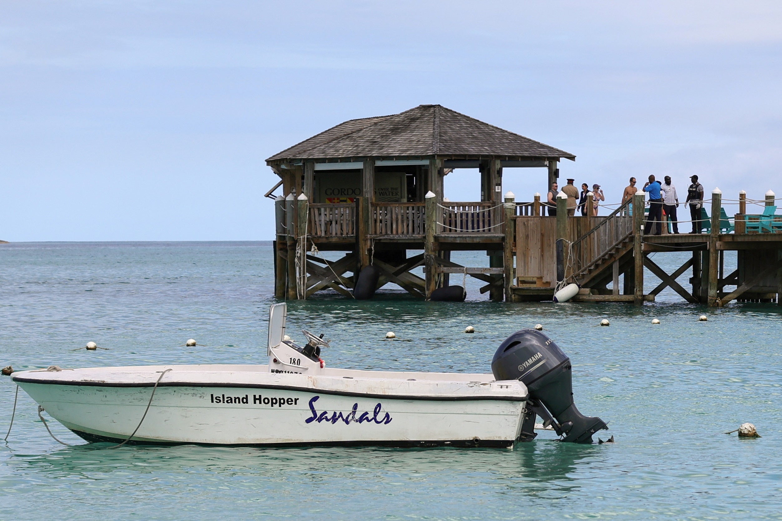 Un grupo de personas se reúne en el muelle del complejo turístico Sandals Royal Bahamian tras el ataque del tiburón.