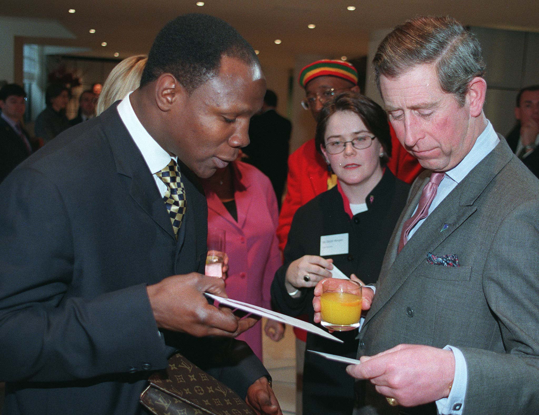 El entonces príncipe Carlos disfrutando de un jugo de naranja junto al boxeador Chris Eubank en una gala sobre el cáncer de mama en 1998.