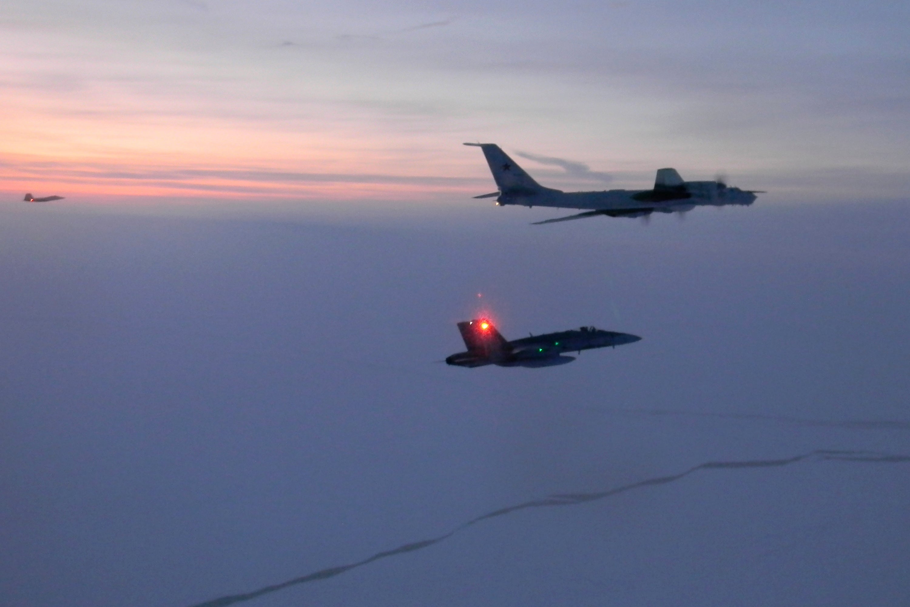 Un avión ruso de reconocimiento marítimo Tu-142, arriba, siendo interceptado cerca de la costa de Alaska