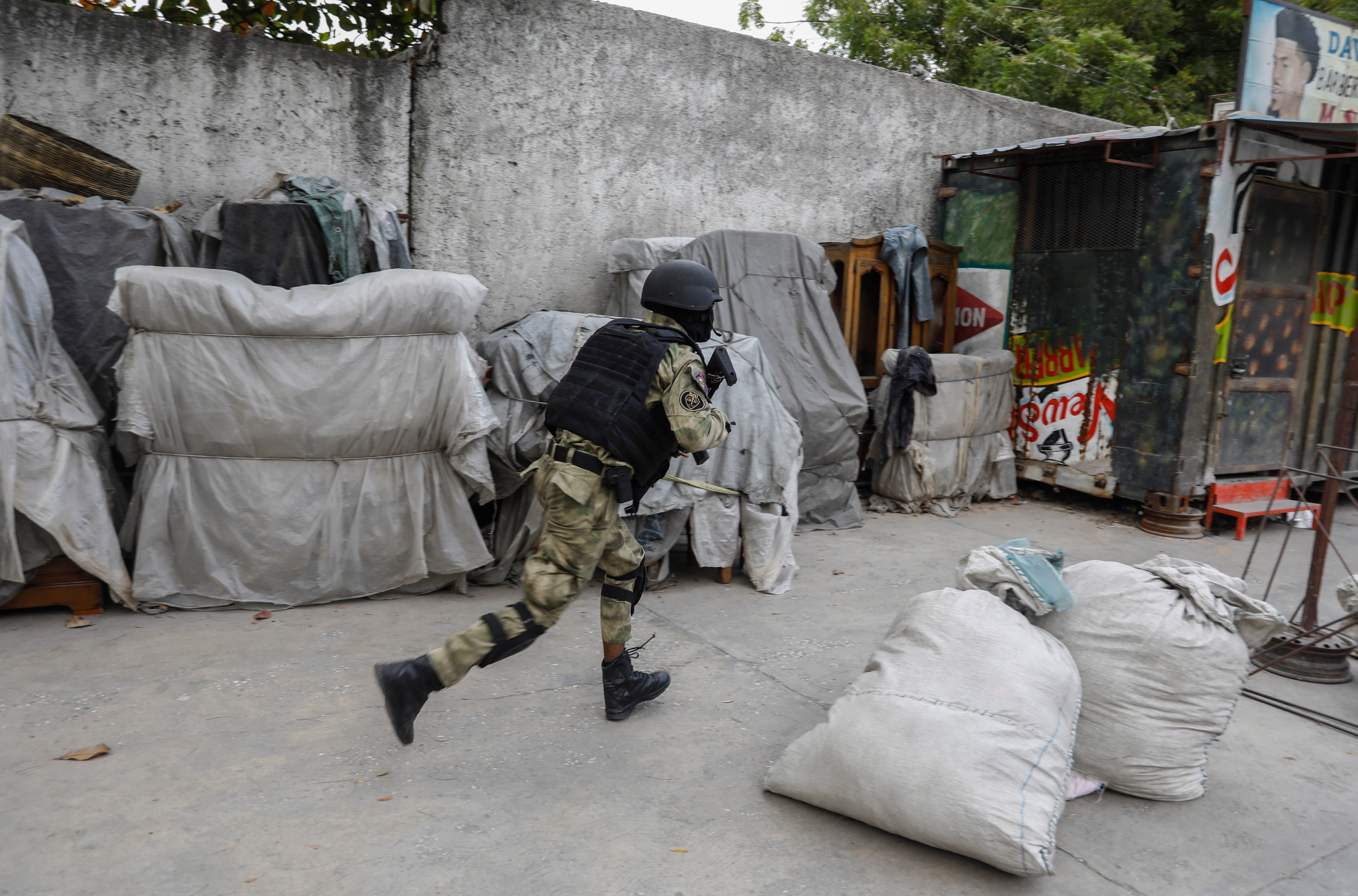 Un agente de policía corre durante una operación antipandillas en el barrio Portail de Puerto Príncipe, Haití