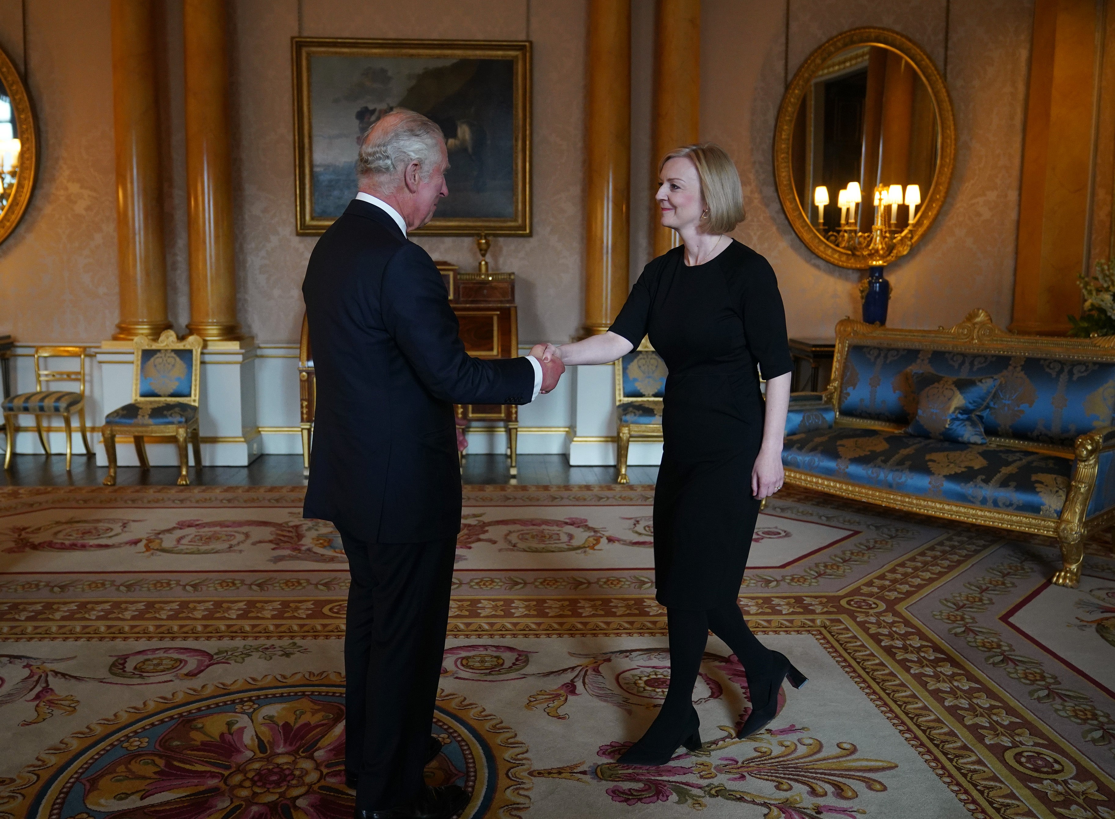 El rey Carlos III da la mano a la ex primera ministra Liz Truss durante su primera audiencia en el palacio de Buckingham