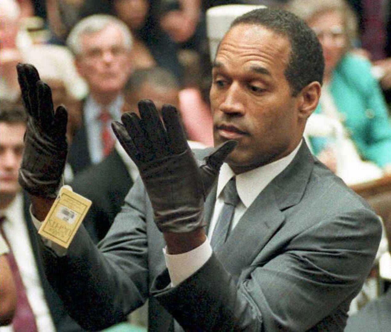 O. J. Simpson examina un par de guantes Aris que los fiscales le hicieron probar el 21 de junio de 1995 durante su juicio por doble asesinato en Los Ángeles.