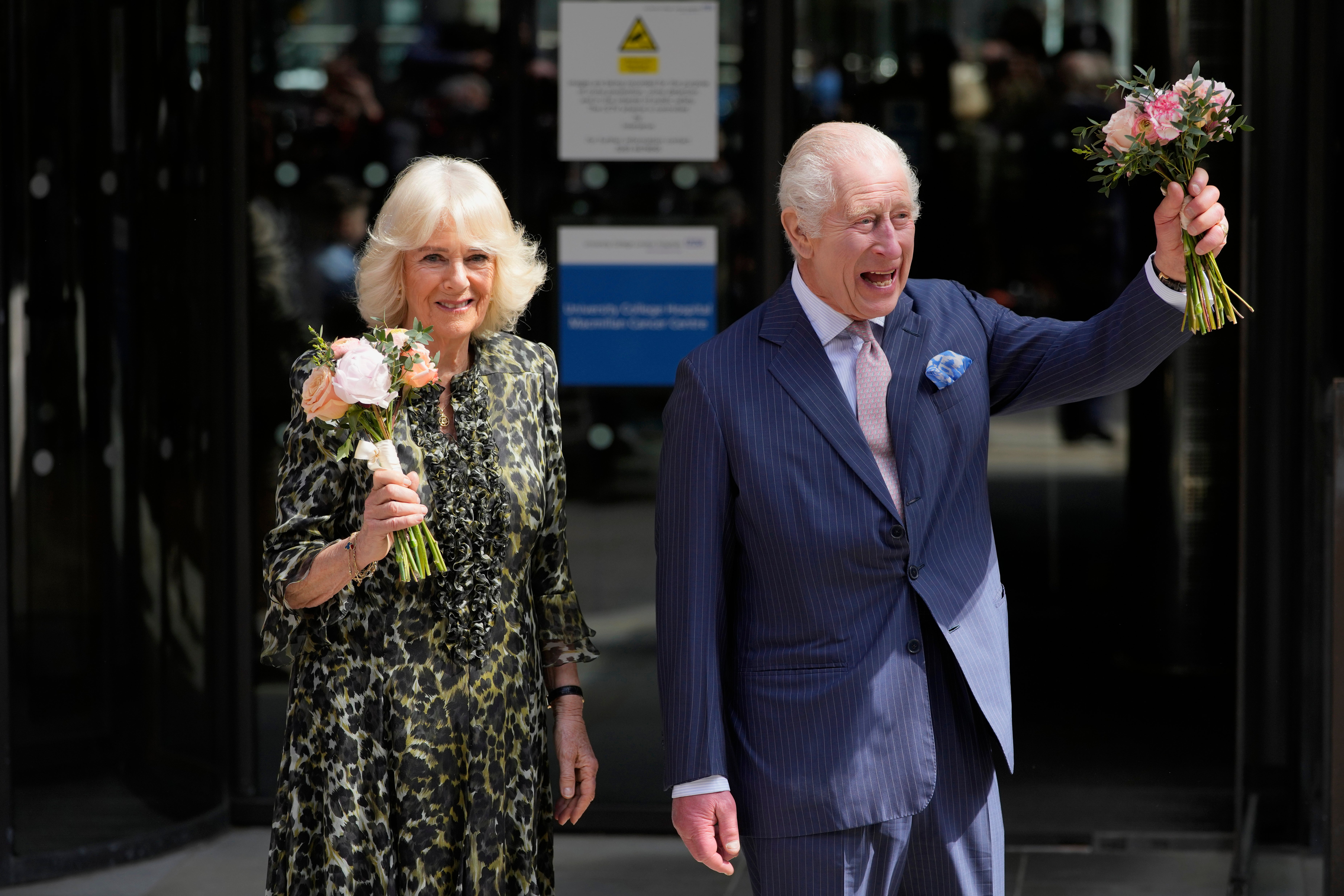 El rey Carlos III y la reina Camila sostienen las flores que les regalaron al marcharse tras la visita del martes
