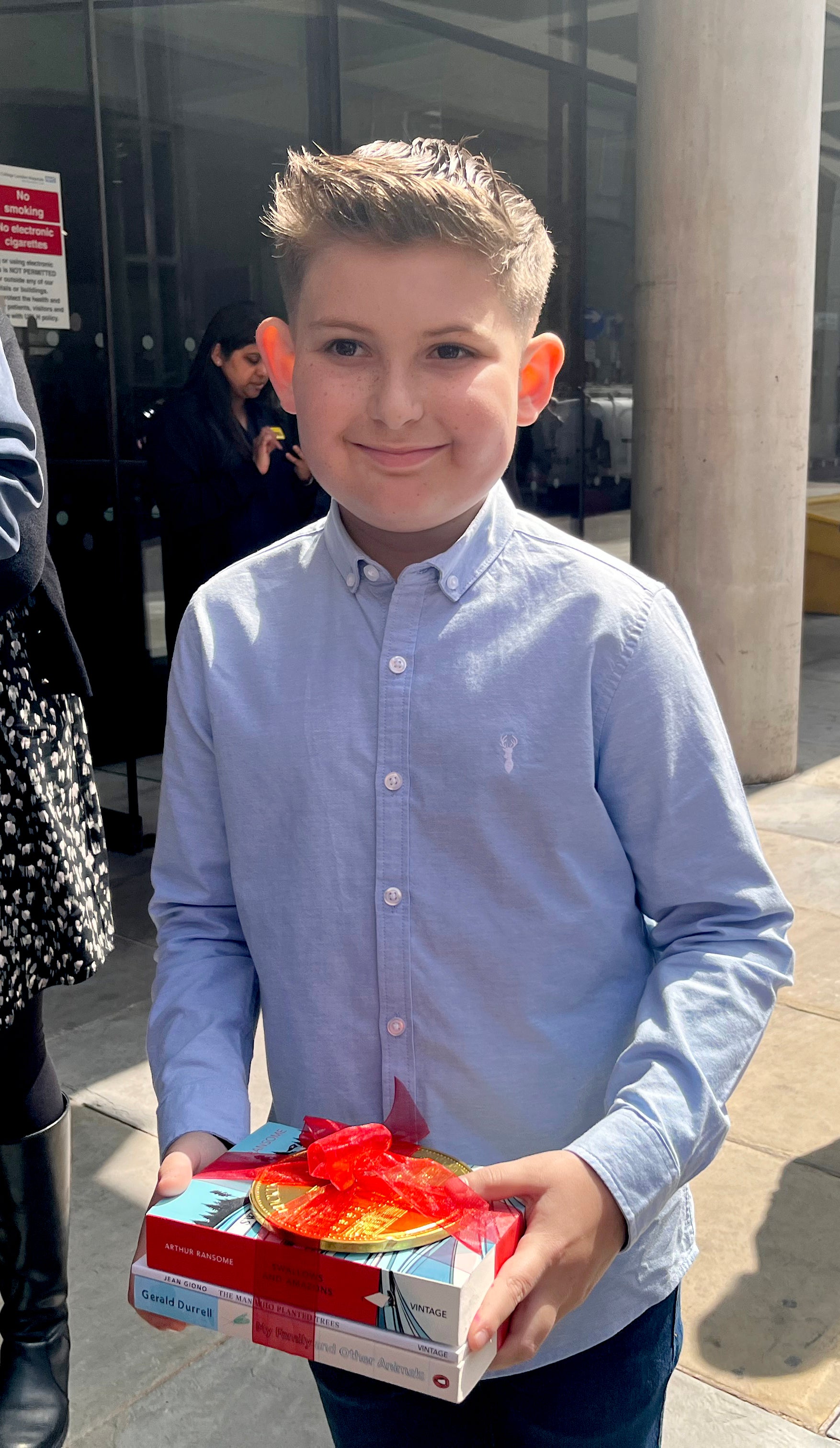 Ellis Edwards, de 11 años, con tres libros y una moneda de chocolate etiquetada del palacio de Buckingham que le regalaron los reyes Carlos III y Camila