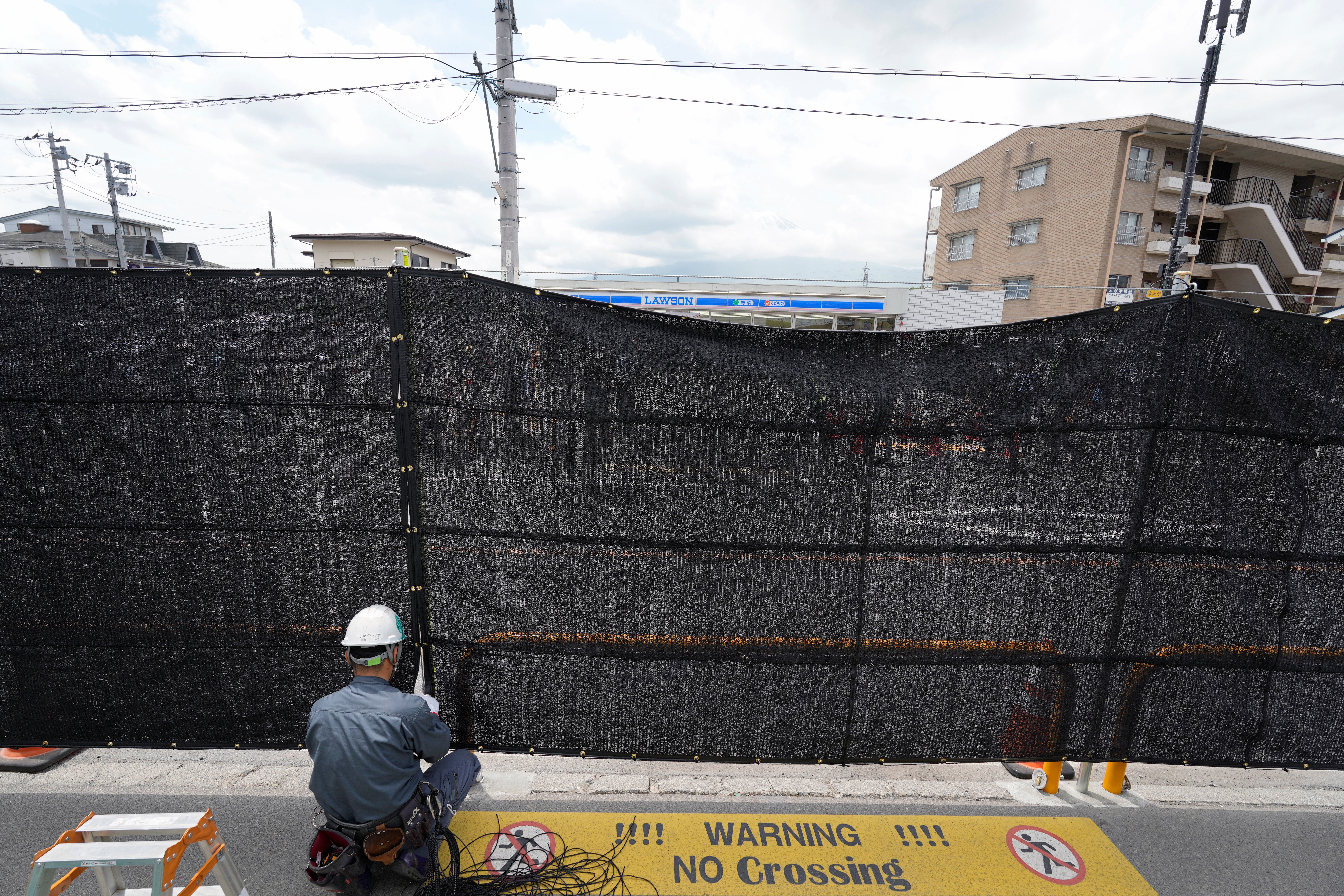 Un trabajador instala una red negra frente a una tienda de comestibles en Fujikawaguchiko