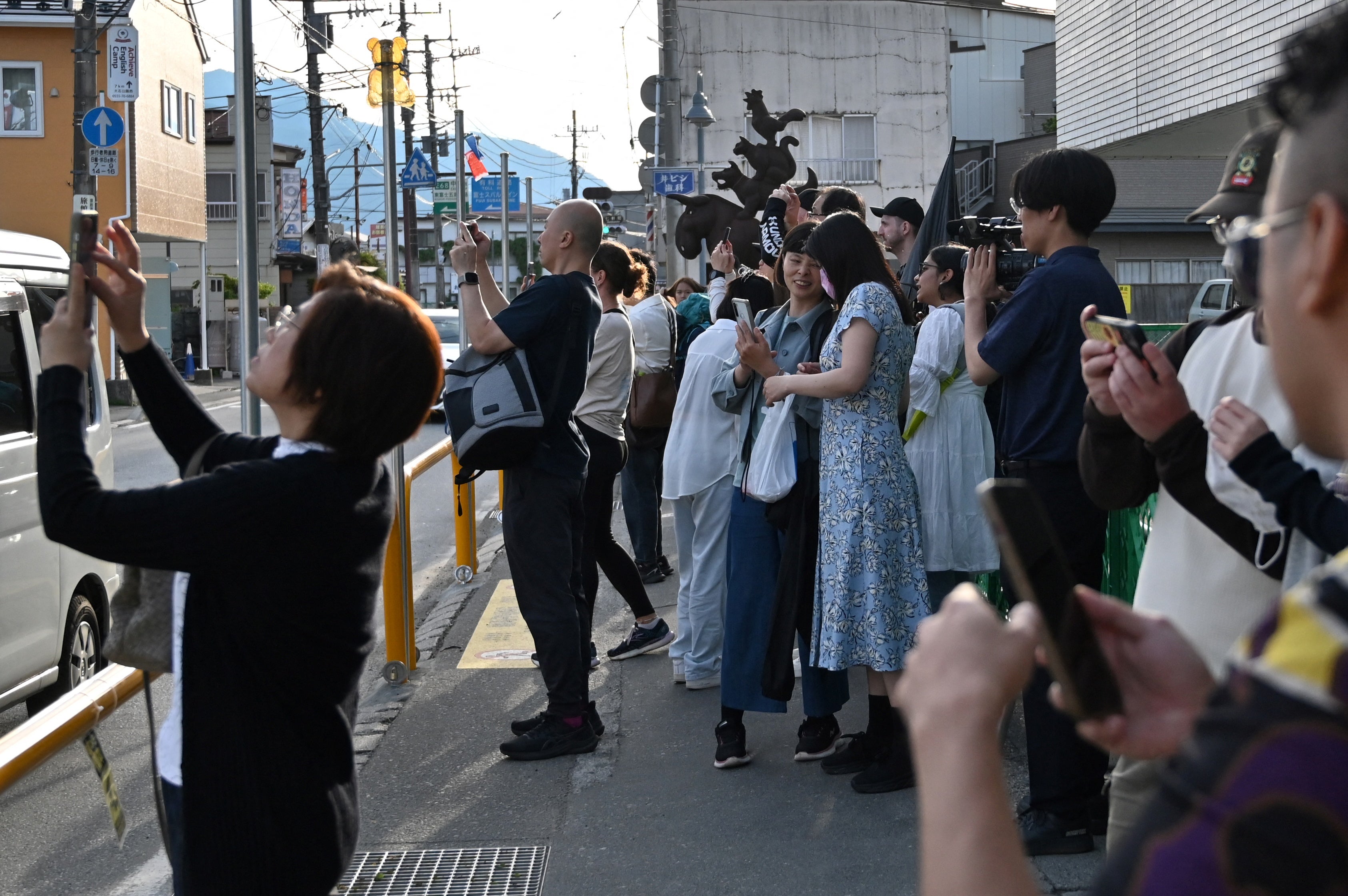 Turistas se amontonan en la acera, frente a una tienda de comestibles ubicada en el pueblo de Fujikawaguchiko, para fotografiar el monte Fuji